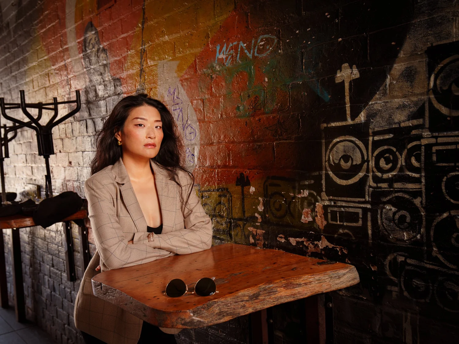 Anna in a blazer at a wooden table with sunglasses in front of her