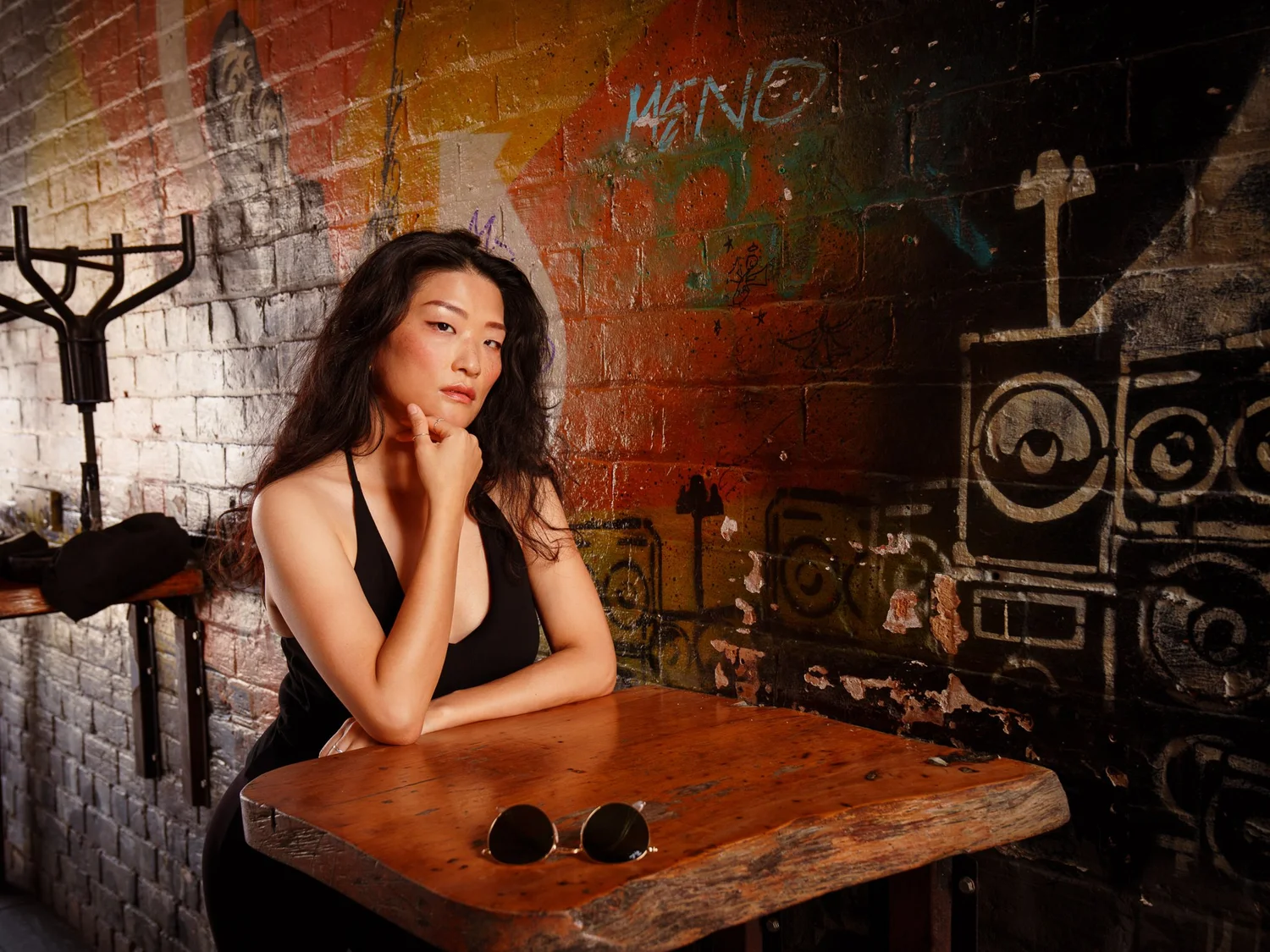 Anna at a wooden table in a graffiti-covered courtyard