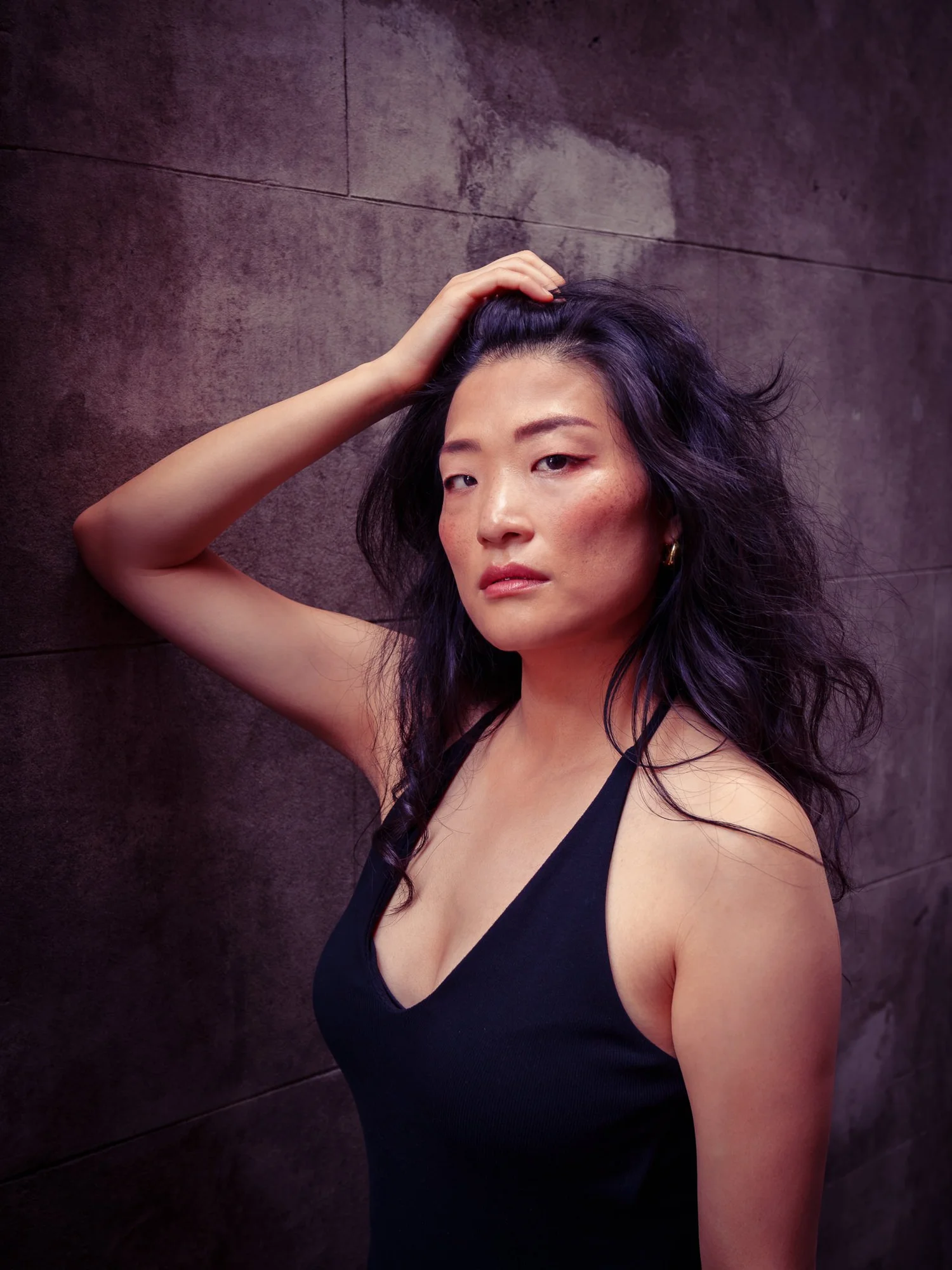 Anna with her hand in her hair against a dark wall
