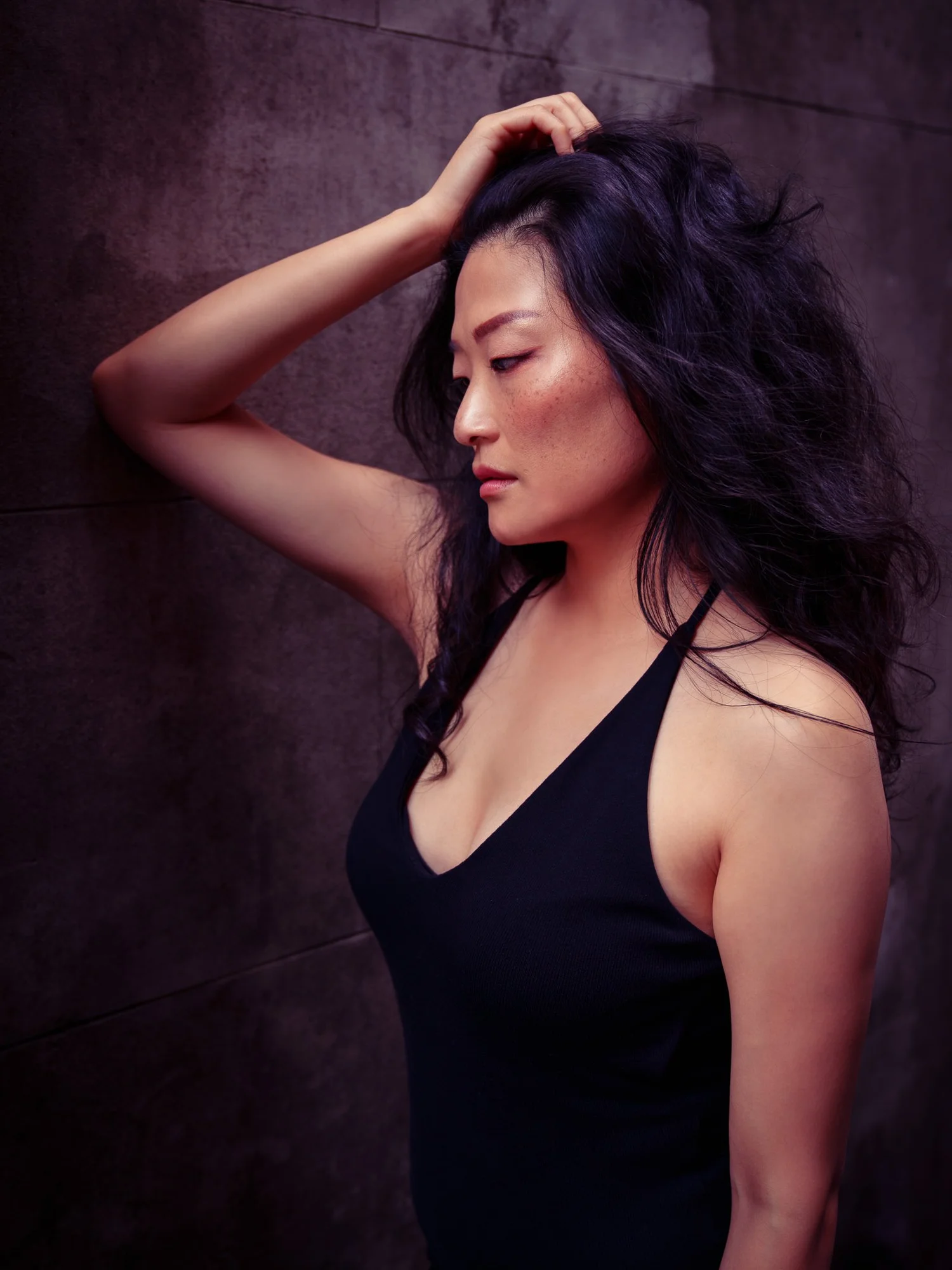 Anna with her hand in her hair against a dark wall