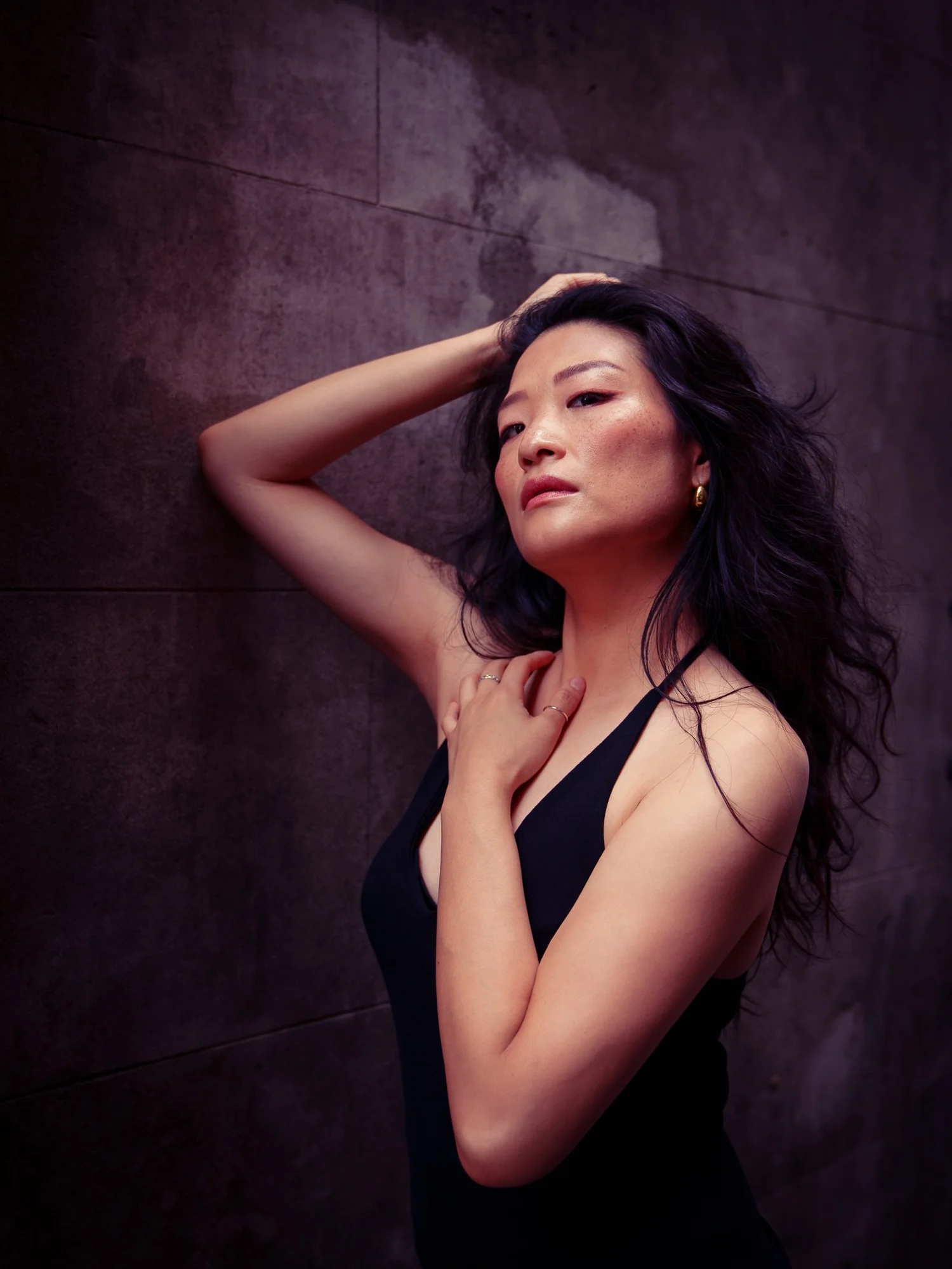 Anna with her hand raised to her hair in dramatic light
