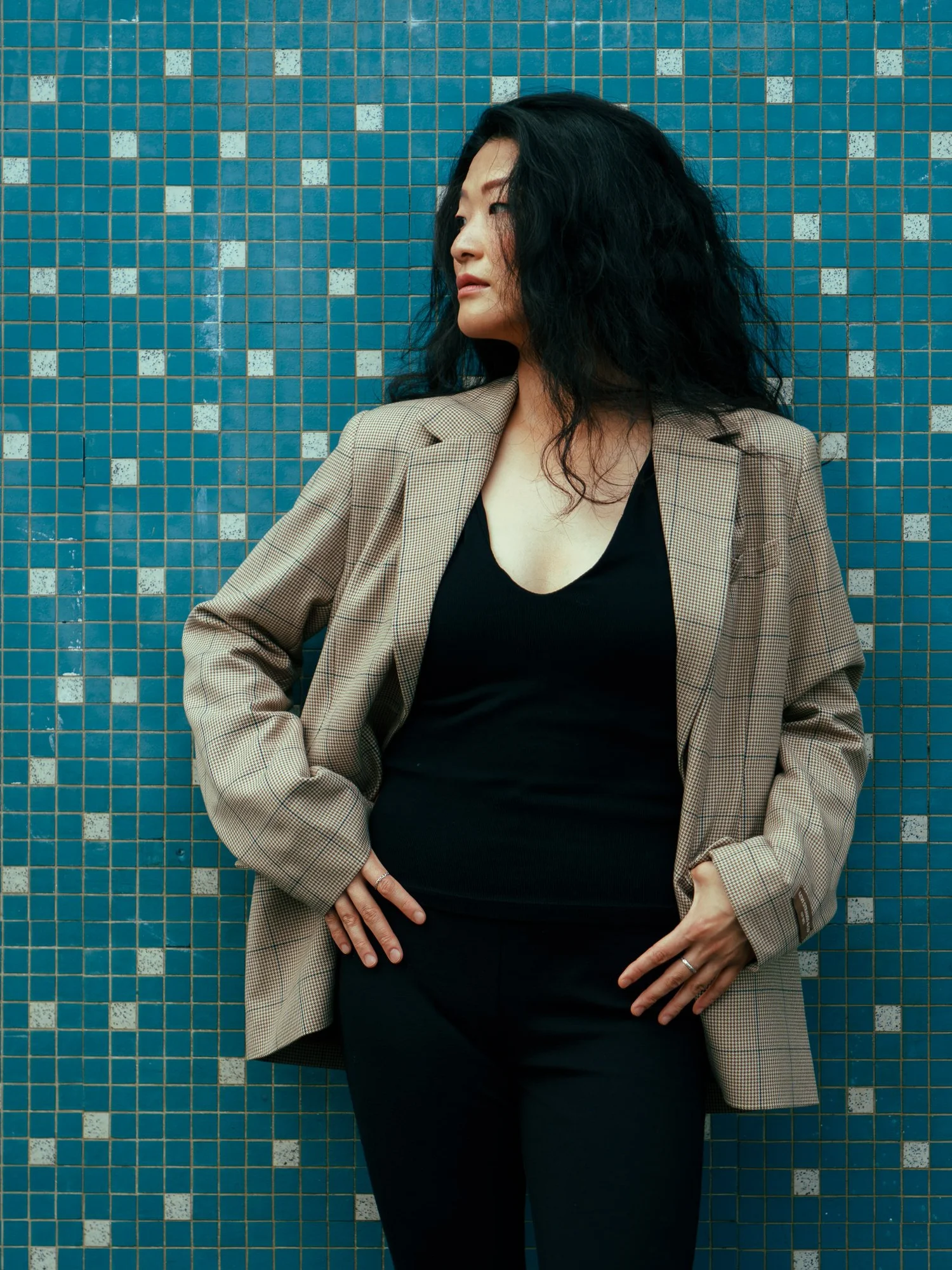 Anna in a blazer with hands on hips against blue tiles