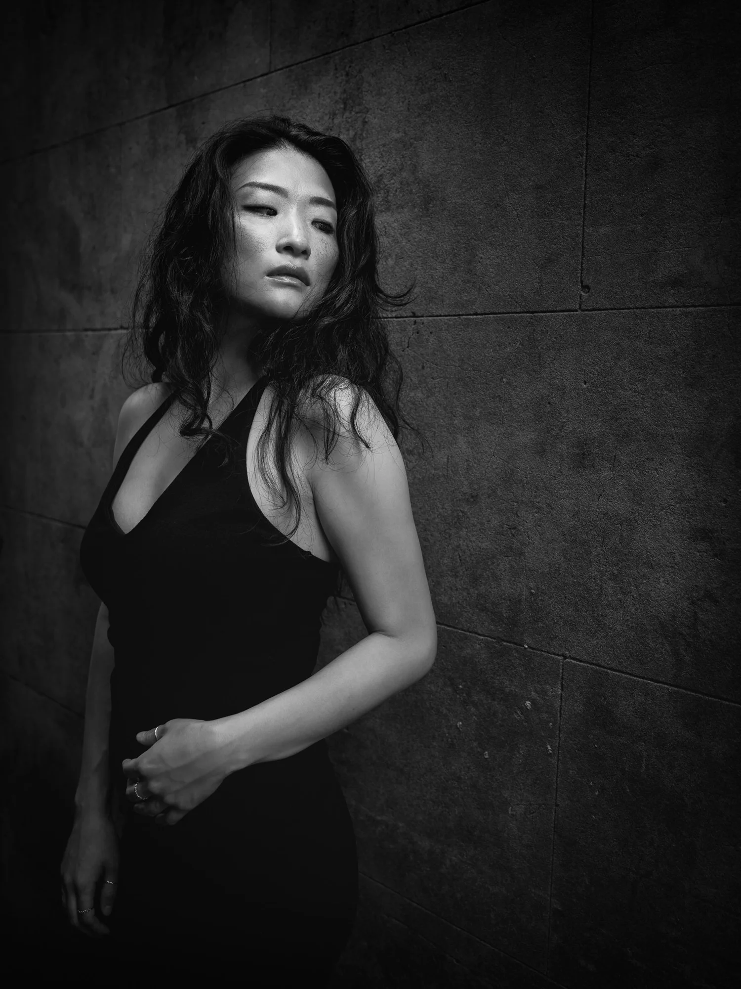 Black and white photo of Anna in a black halter top against a concrete wall