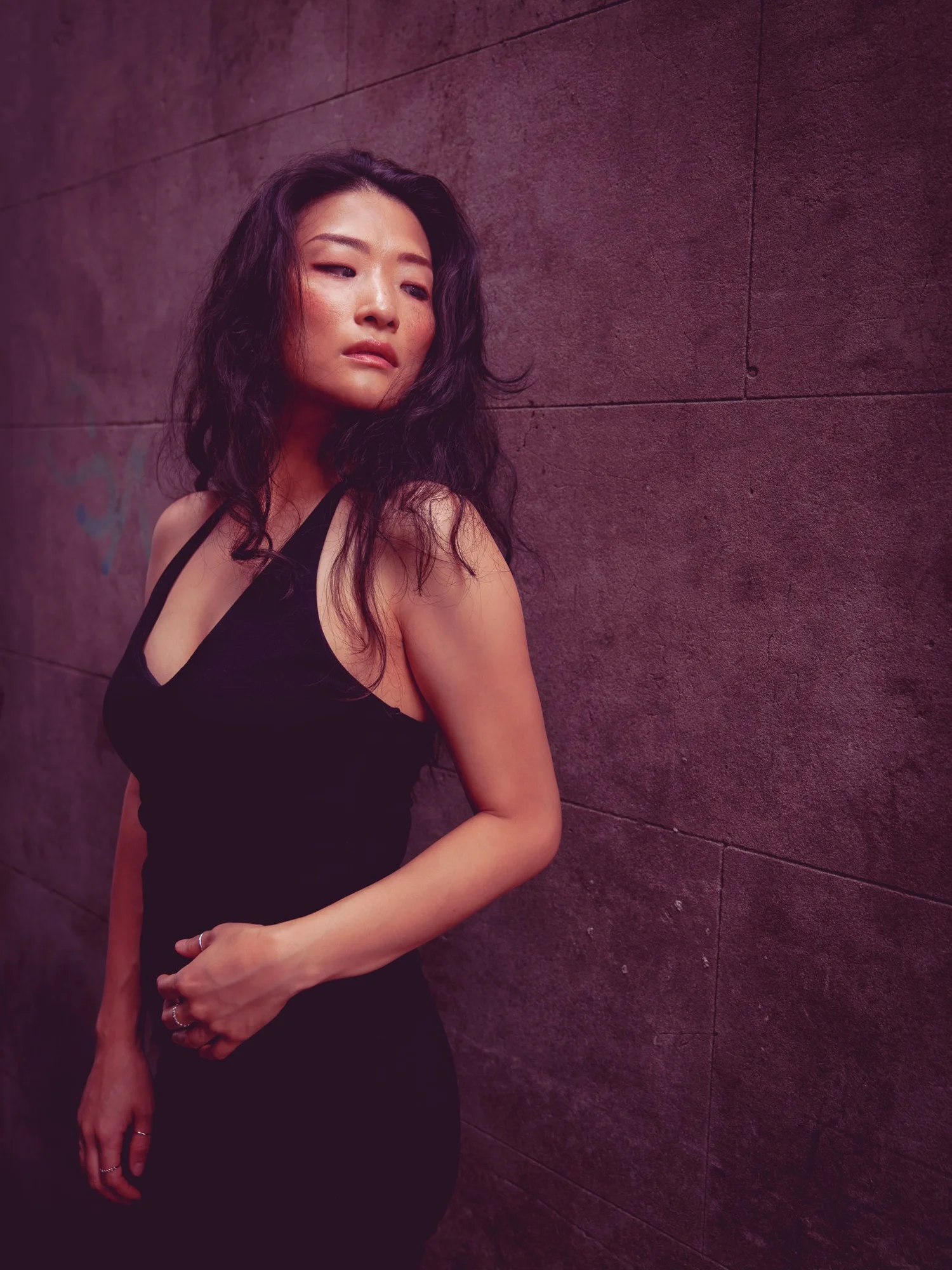Anna in a black halter top against a purple-toned wall