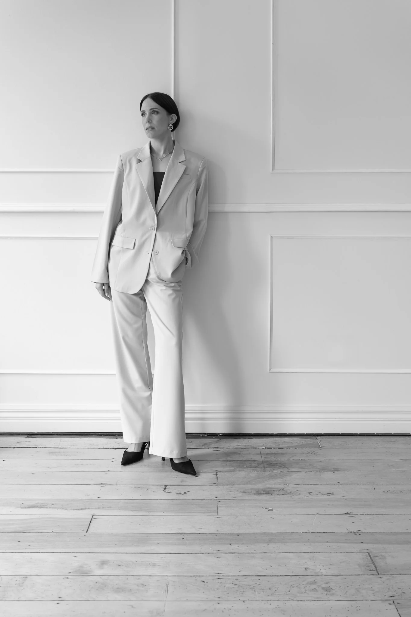 Black and white photo of Nat leaning on a panelled wall