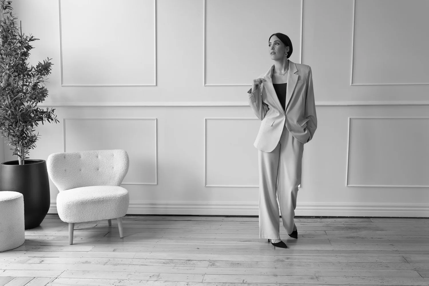 Black and white photo of Nat walking in a cream suit