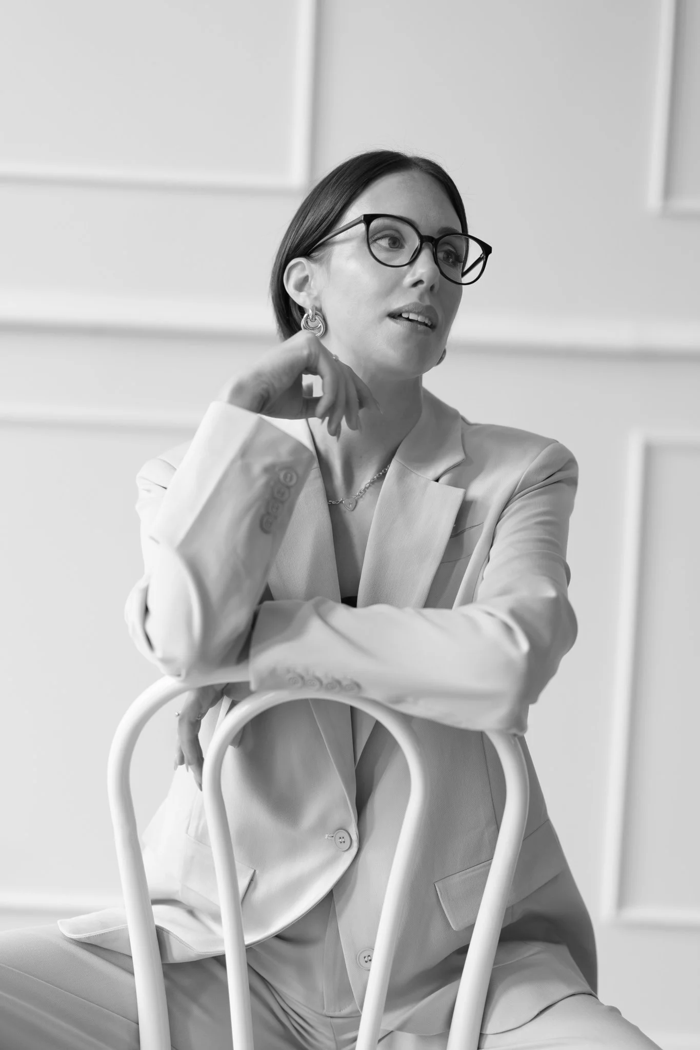 Black and white photo of Nat in glasses touching her earring