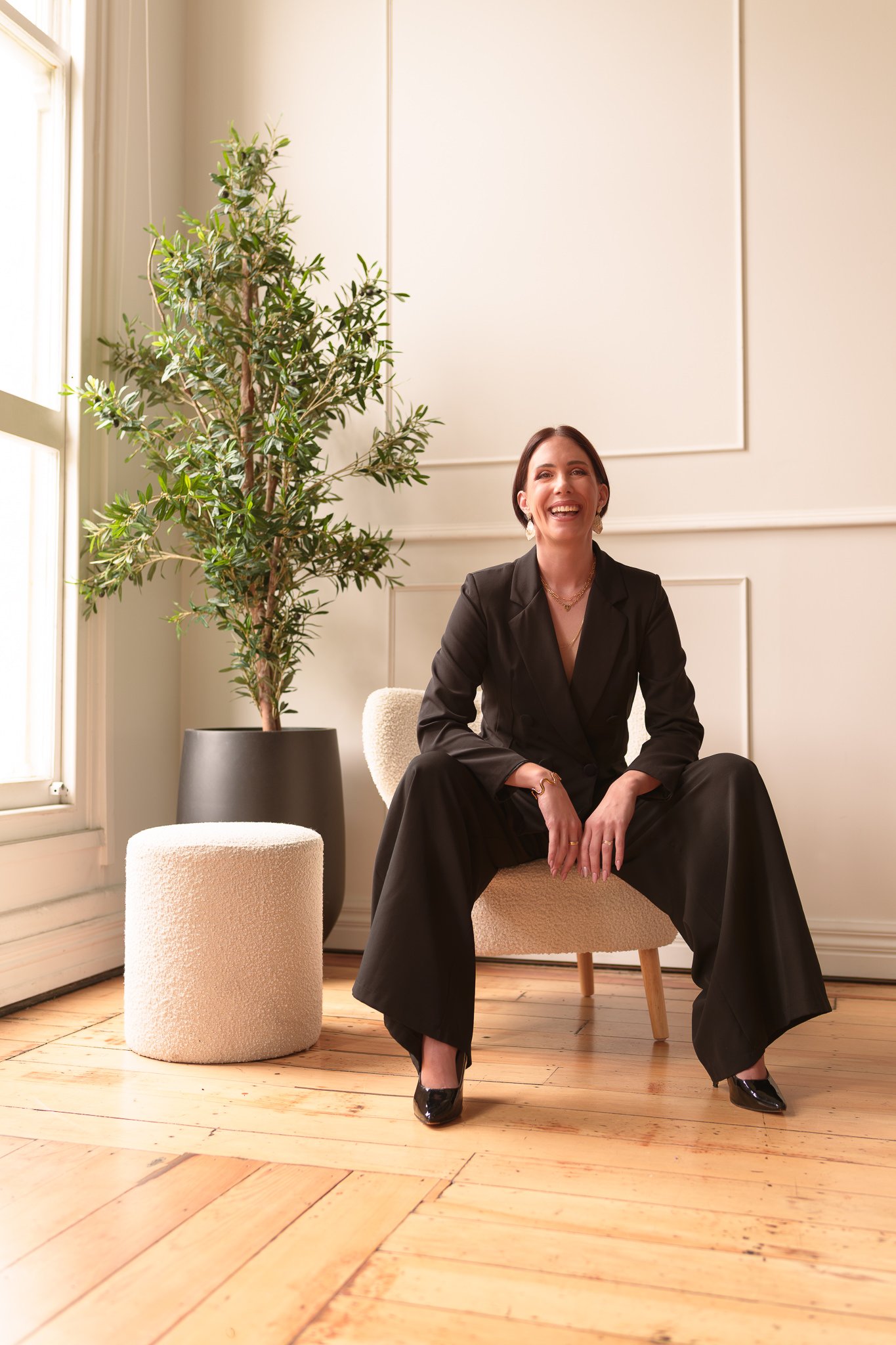 Nat smiles seated in a black suit