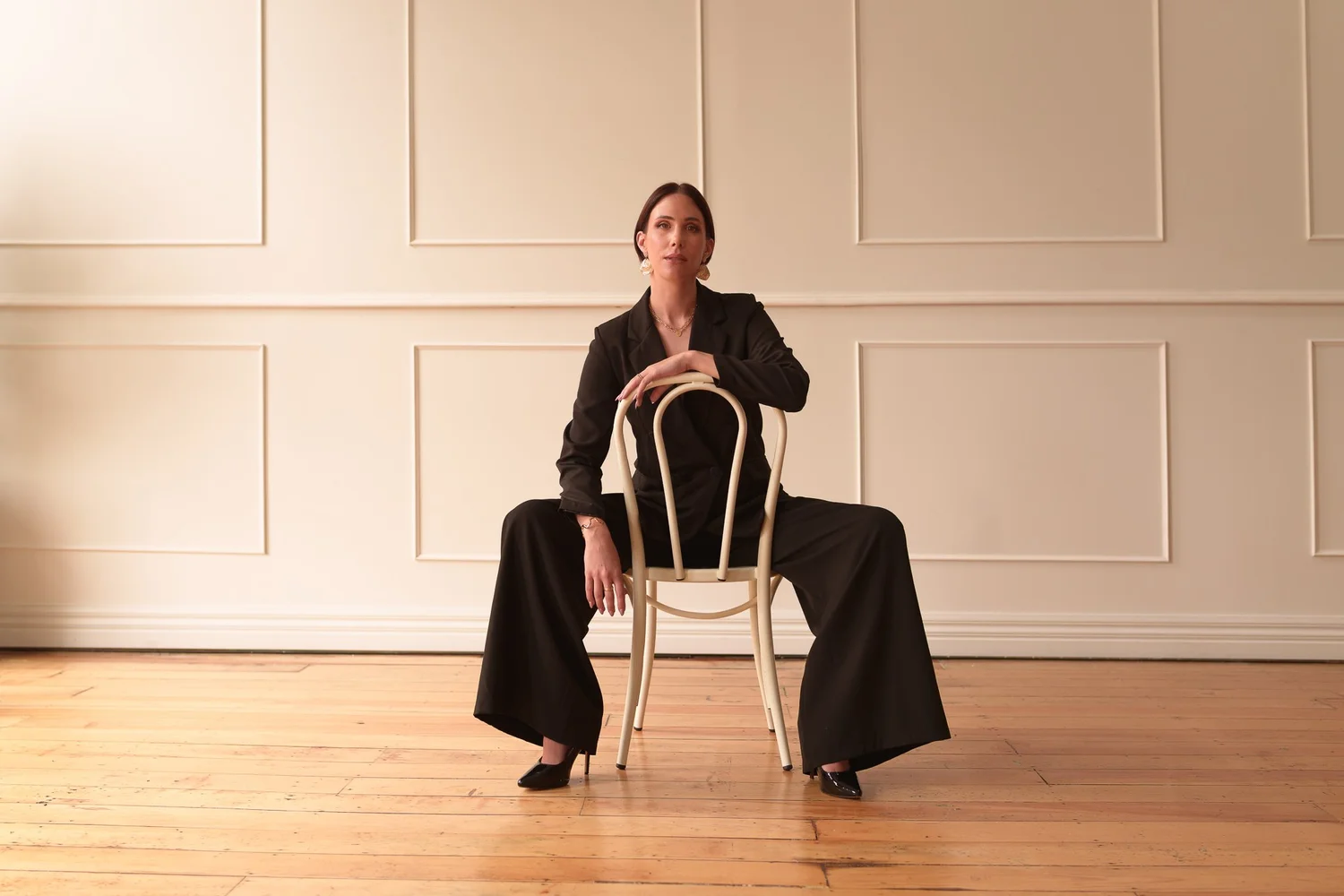 Nat seated on a bentwood chair in an empty panelled room