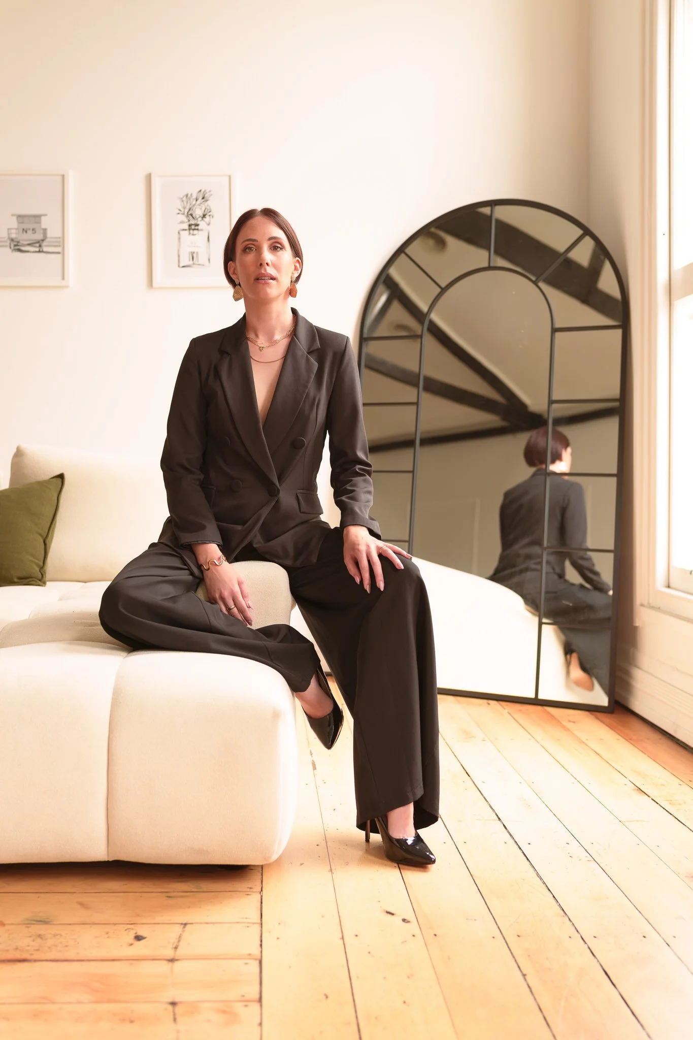 Nat in a black suit sitting on a white sofa
