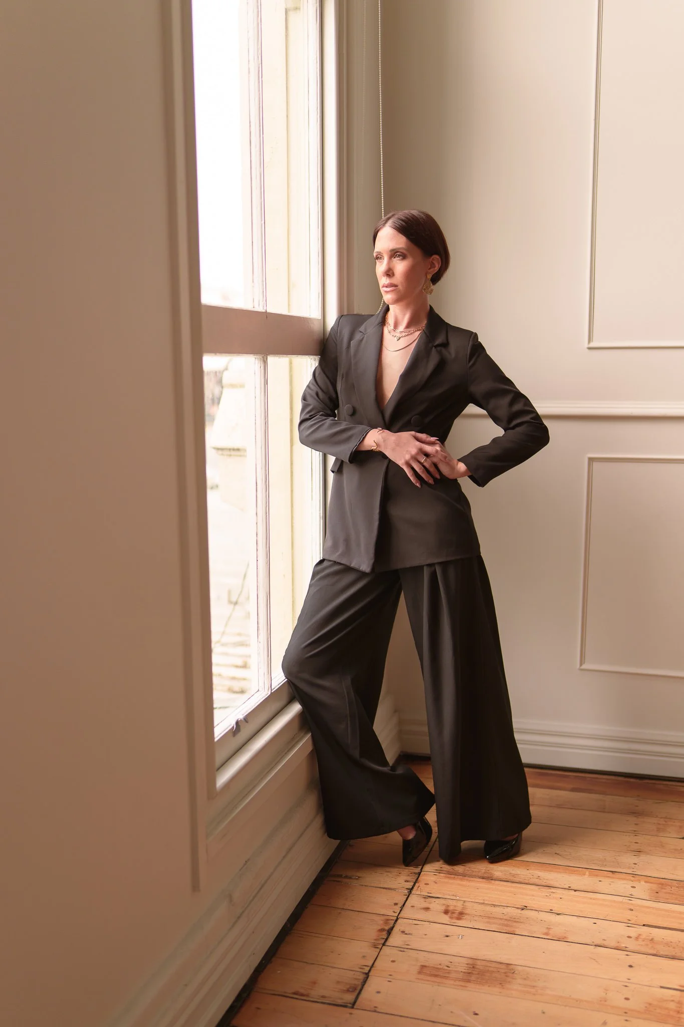Nat with a hand on her hip beside a tall window