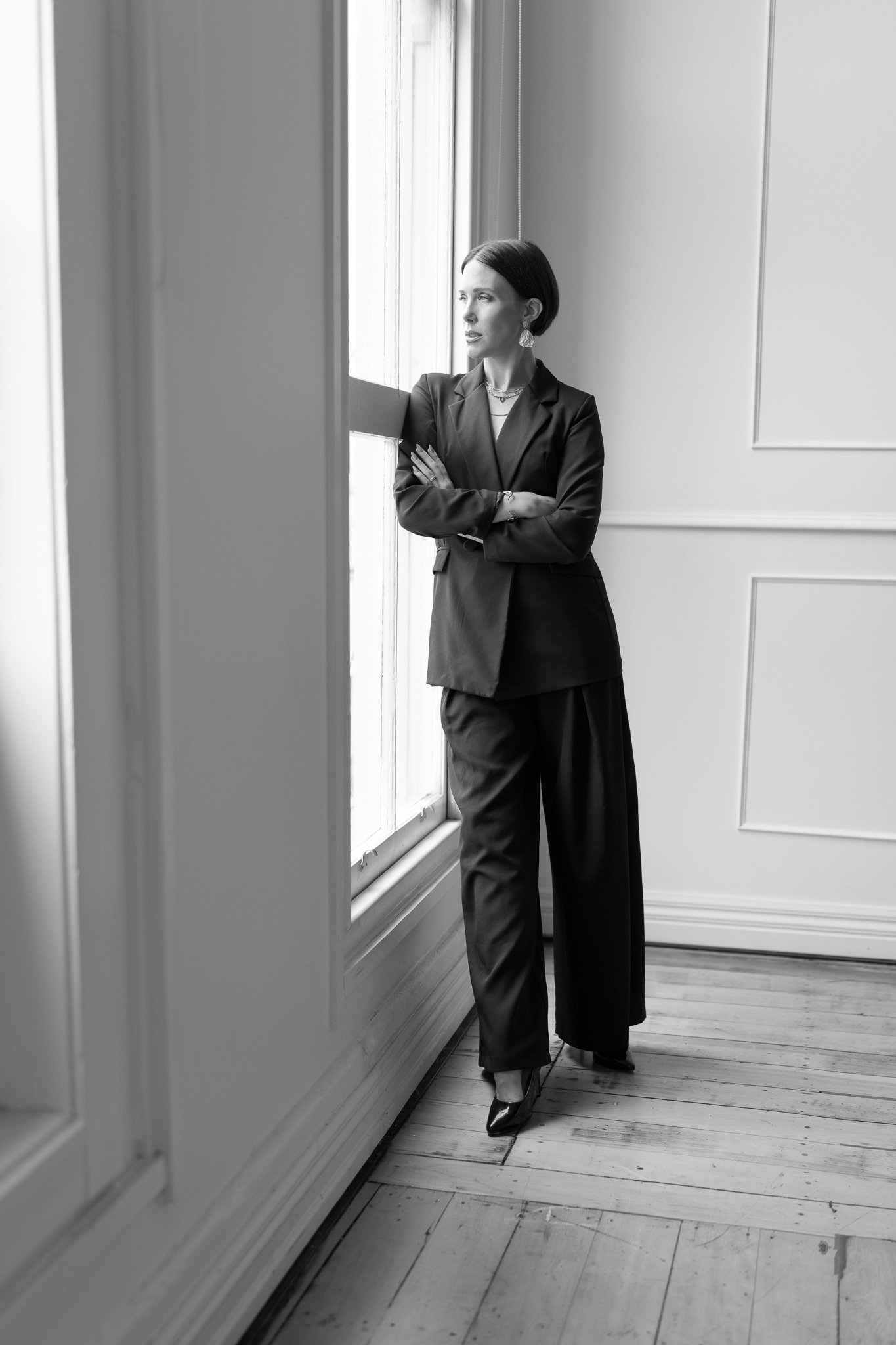 Black and white photo of Nat with folded arms by the window