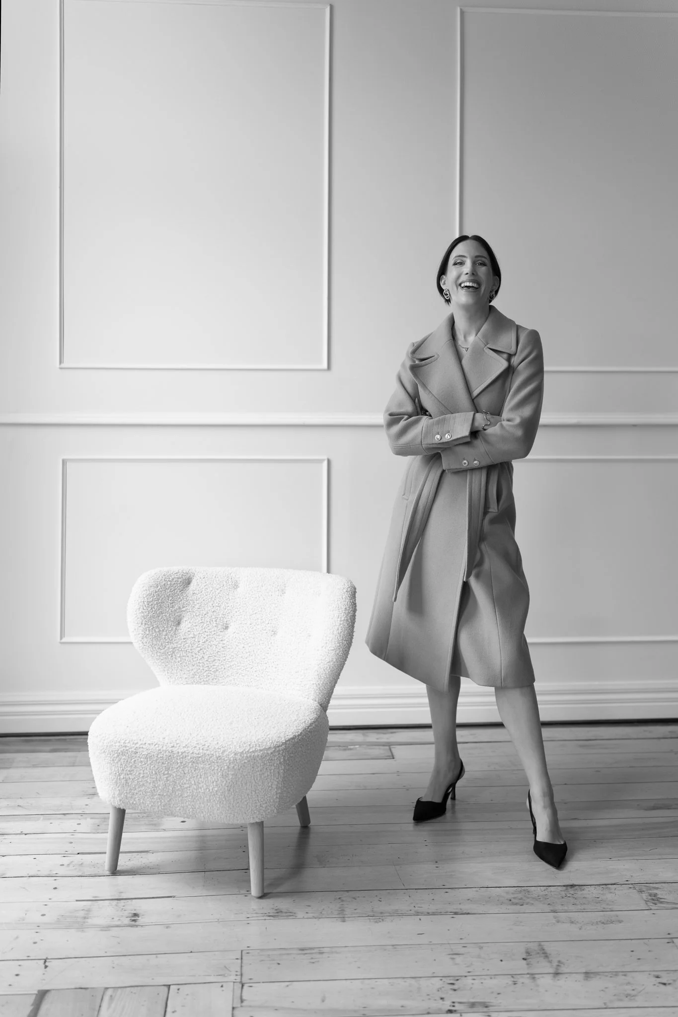 Black and white photo of Nat laughing in a wrap coat