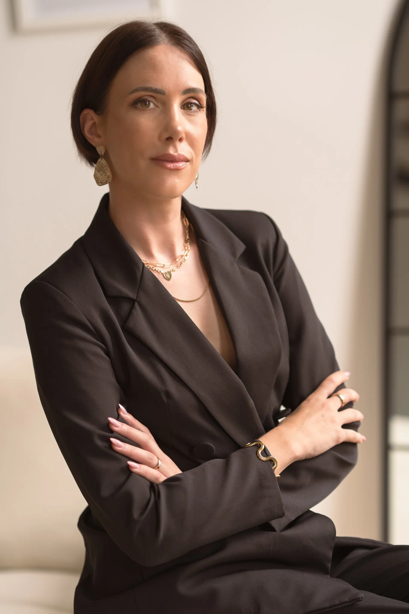 Professional portrait of Nat in a black blazer with arms folded