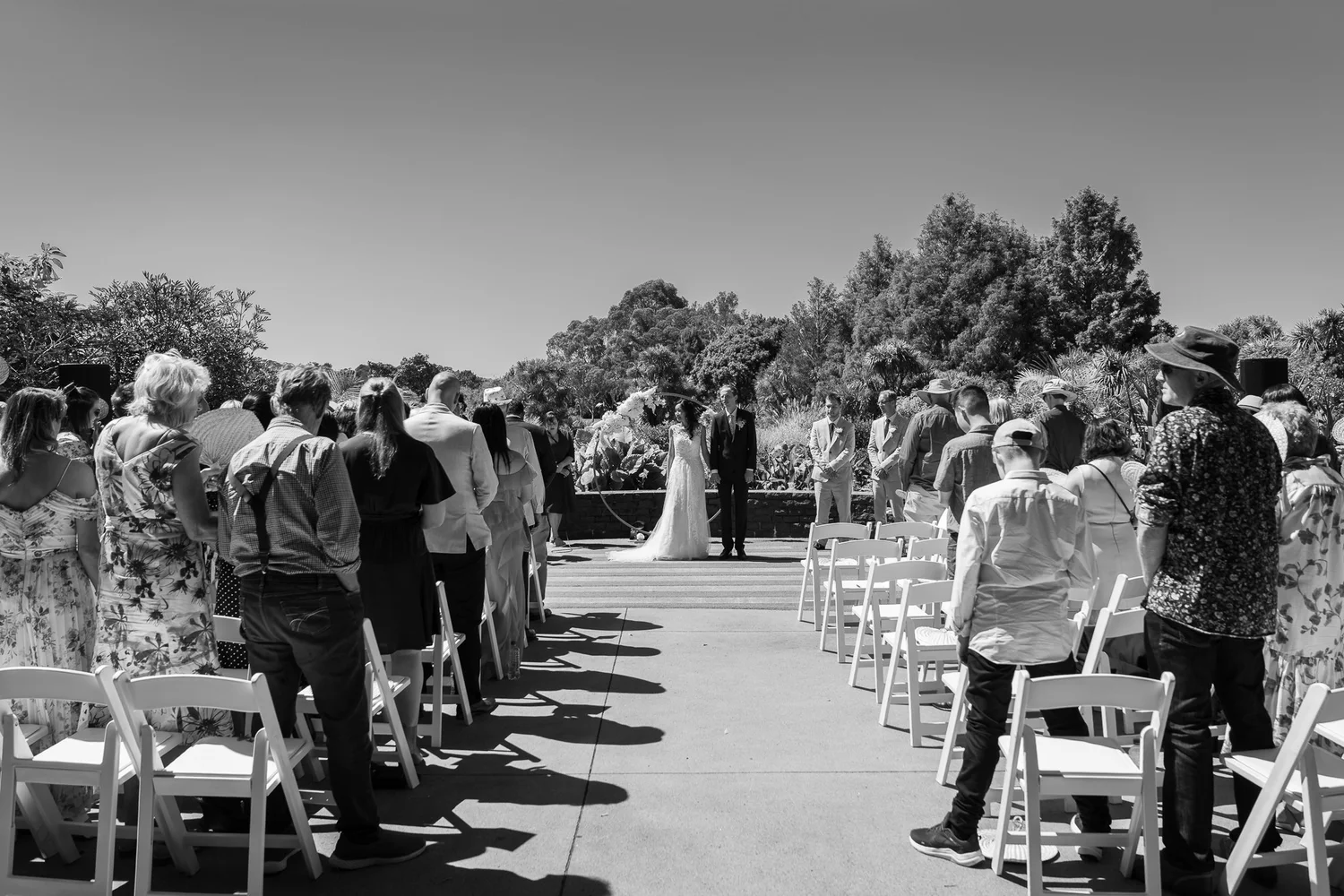 Black and white photo of guests watching Gel walk down the aisle