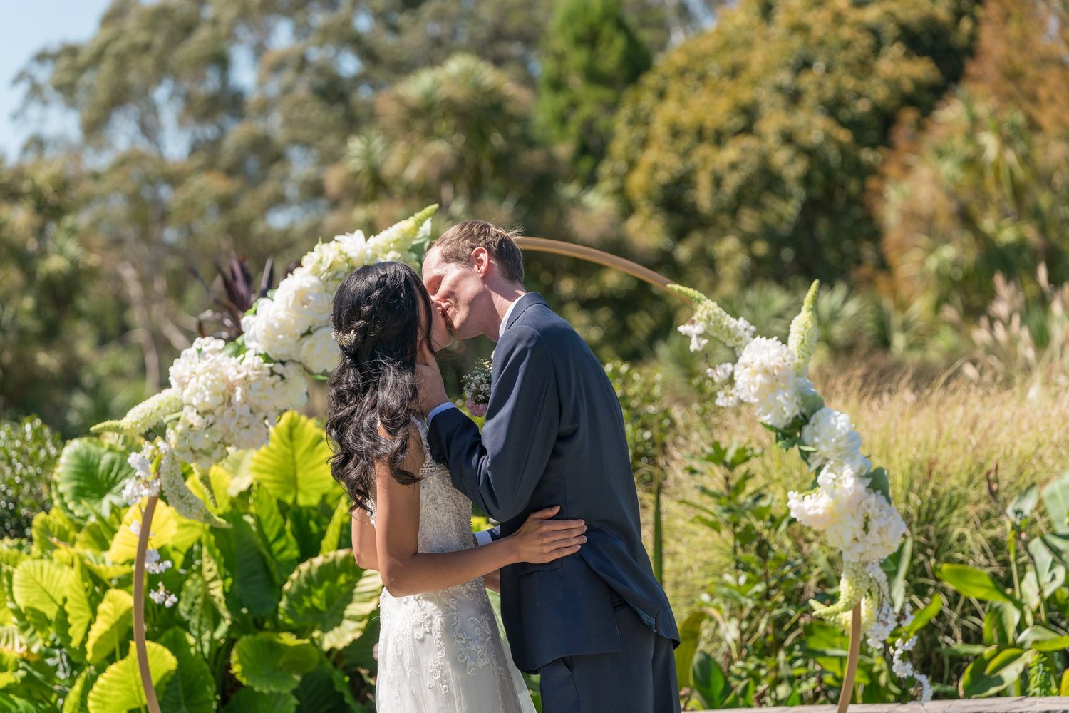 Gel and James kiss under the floral hoop