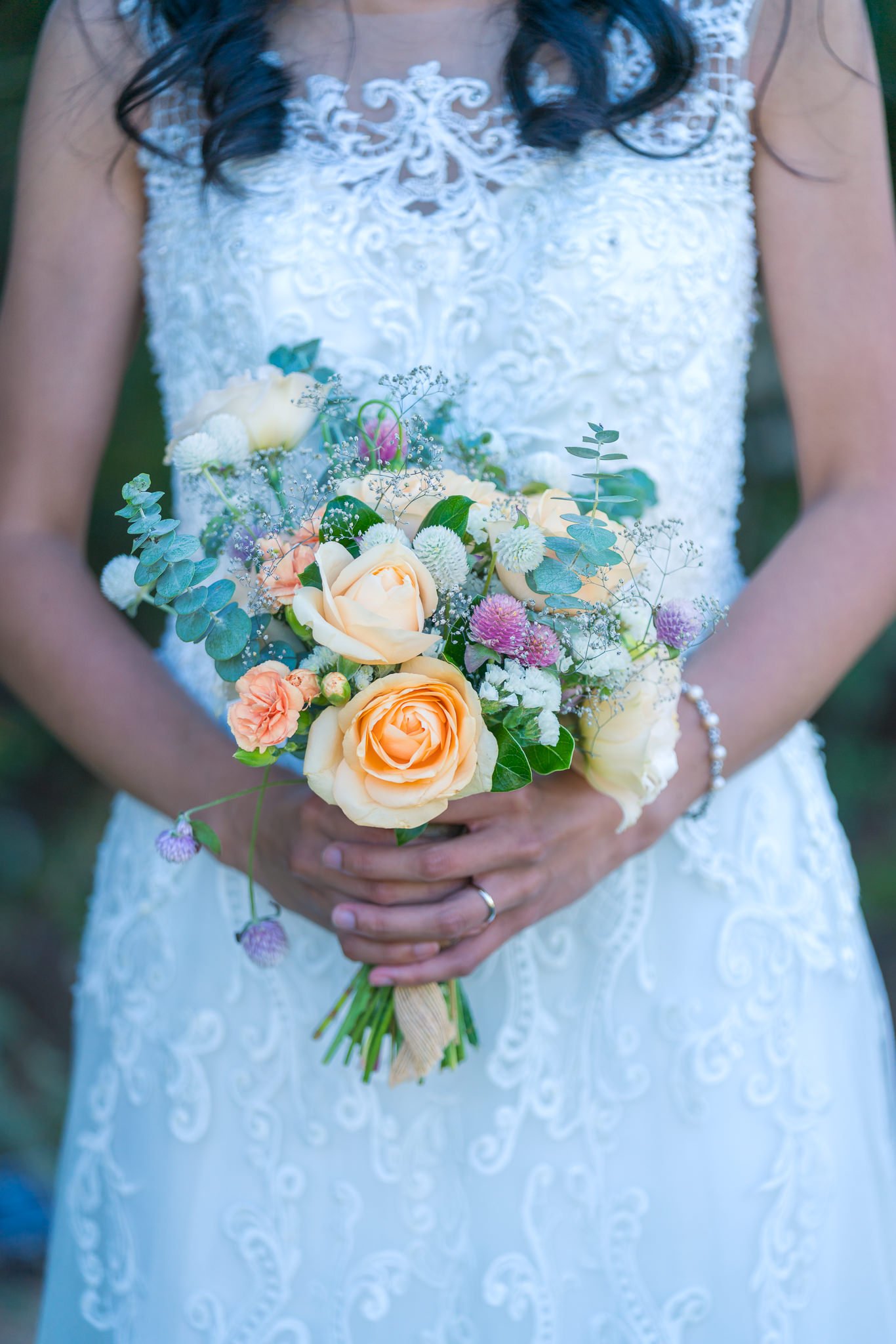 Gel holds her pastel bouquet against her lace gown