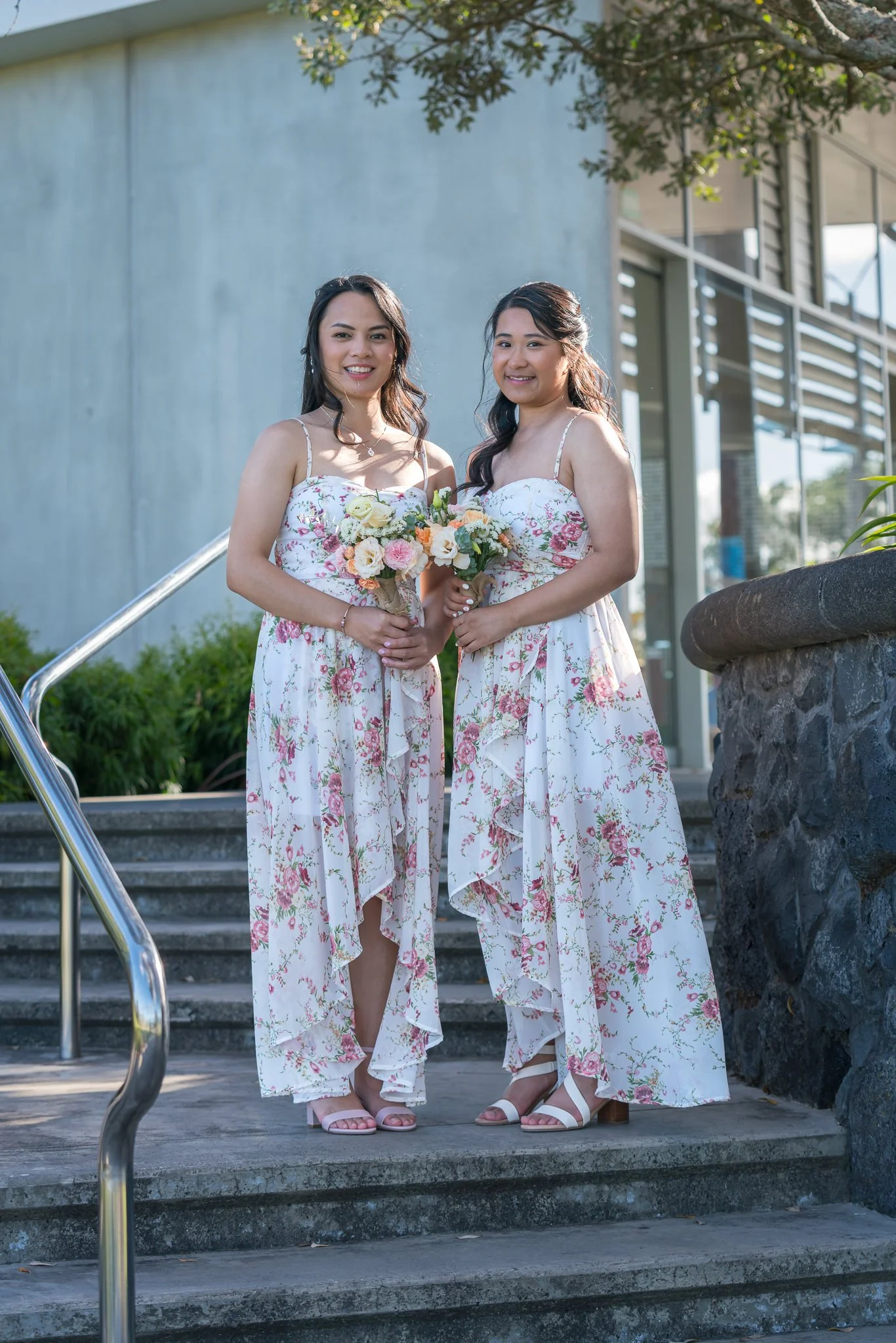 Two bridesmaids in floral dresses on the steps