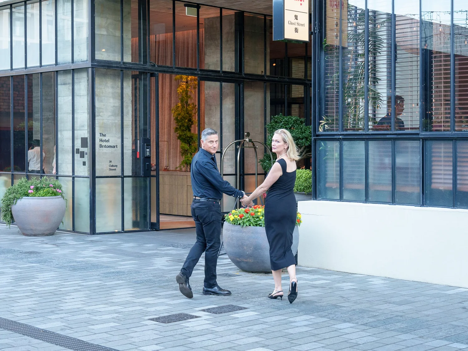 The couple dance hand in hand across a paved street