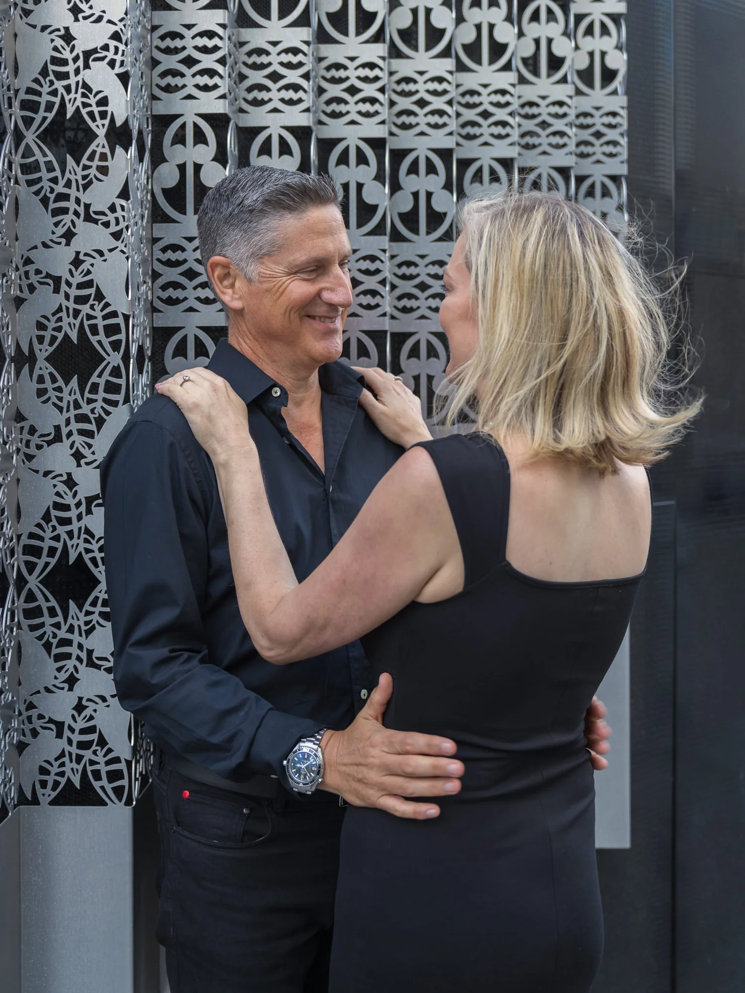 The couple face each other against a patterned wall