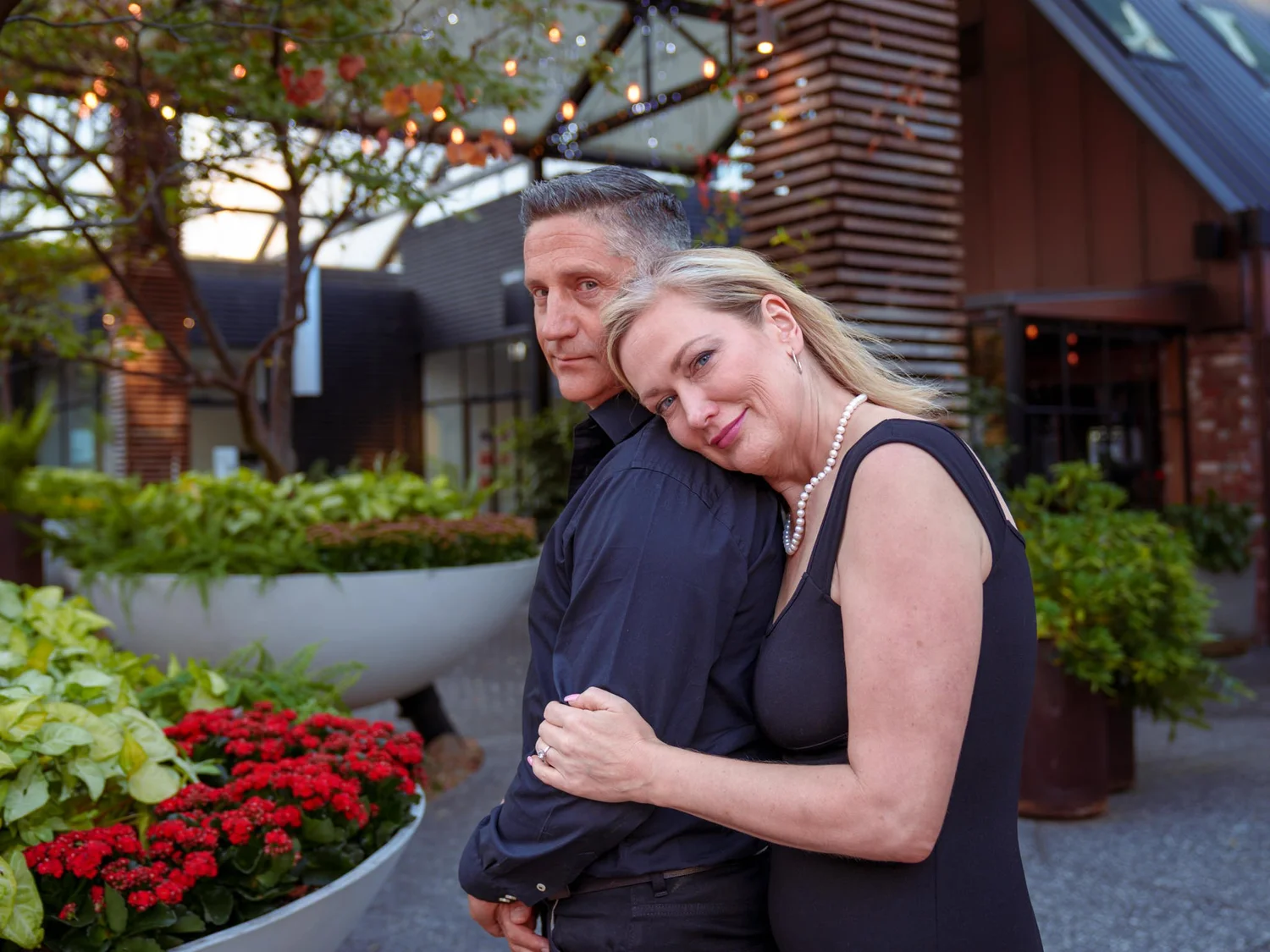 She rests her head on his shoulder among the planters
