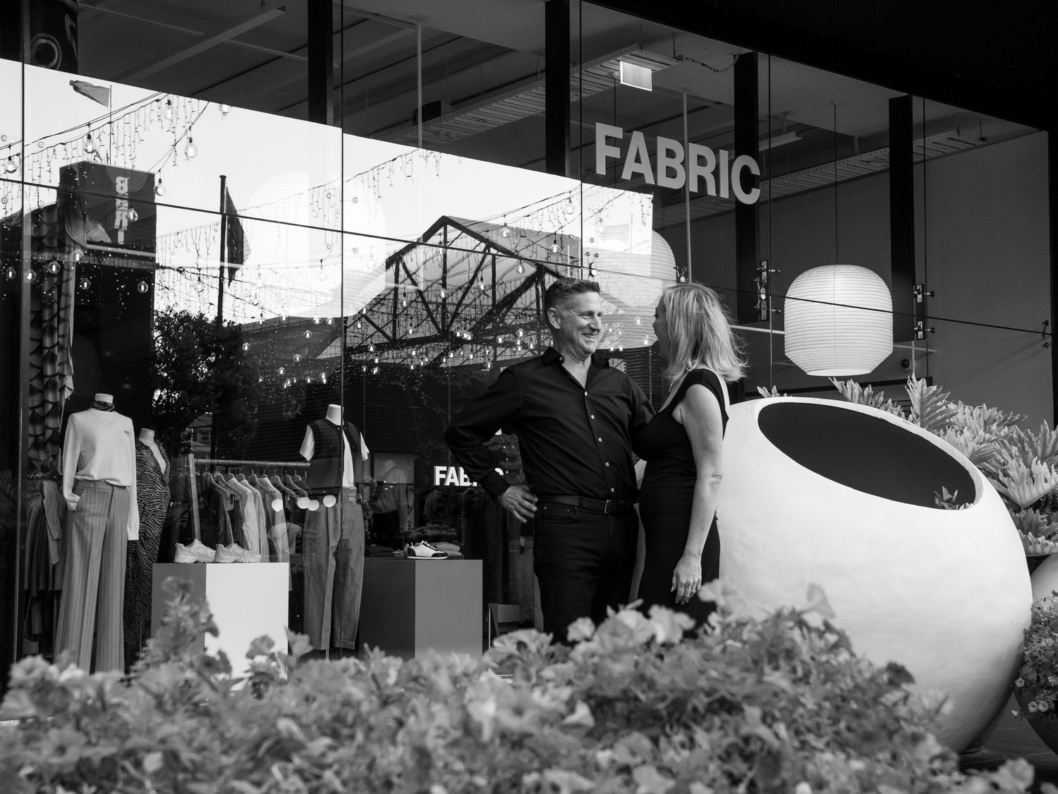 Black and white photo of the couple outside a shop front
