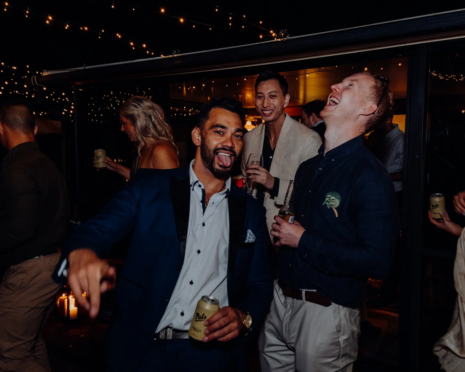 Guests laugh together under festoon lights at night