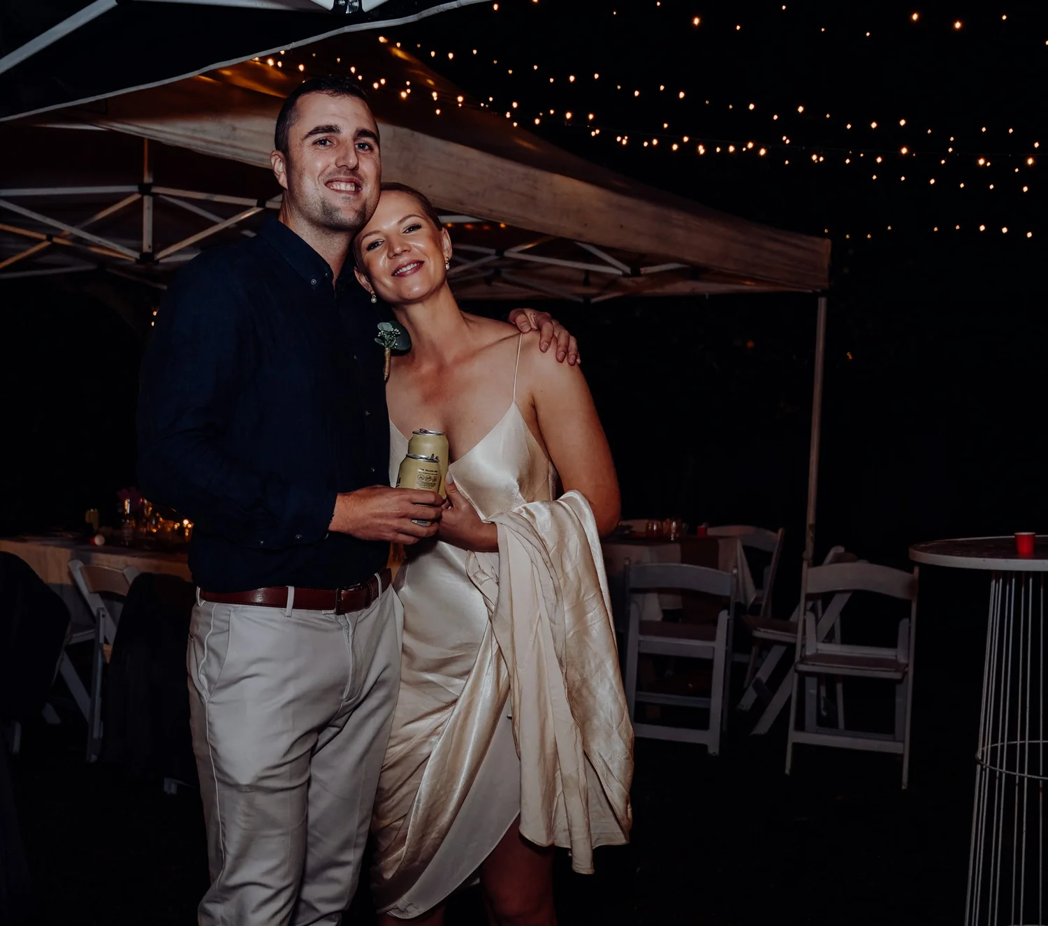 Rebecca and Michael laugh together under fairy lights