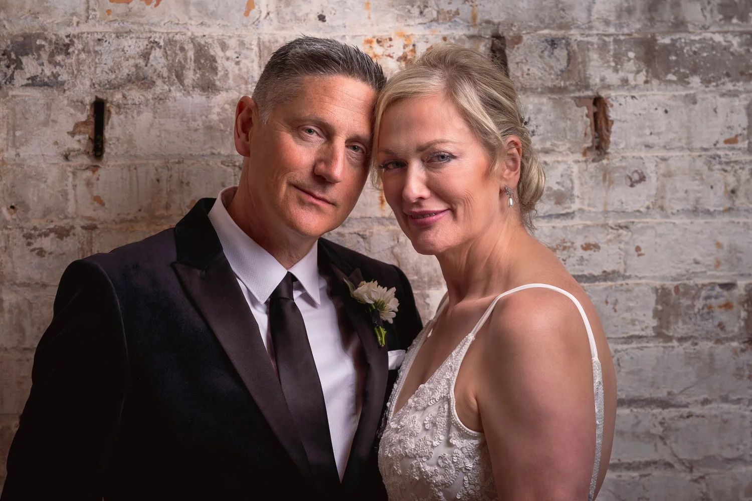 Darren and Shannon cheek to cheek against whitewashed brick