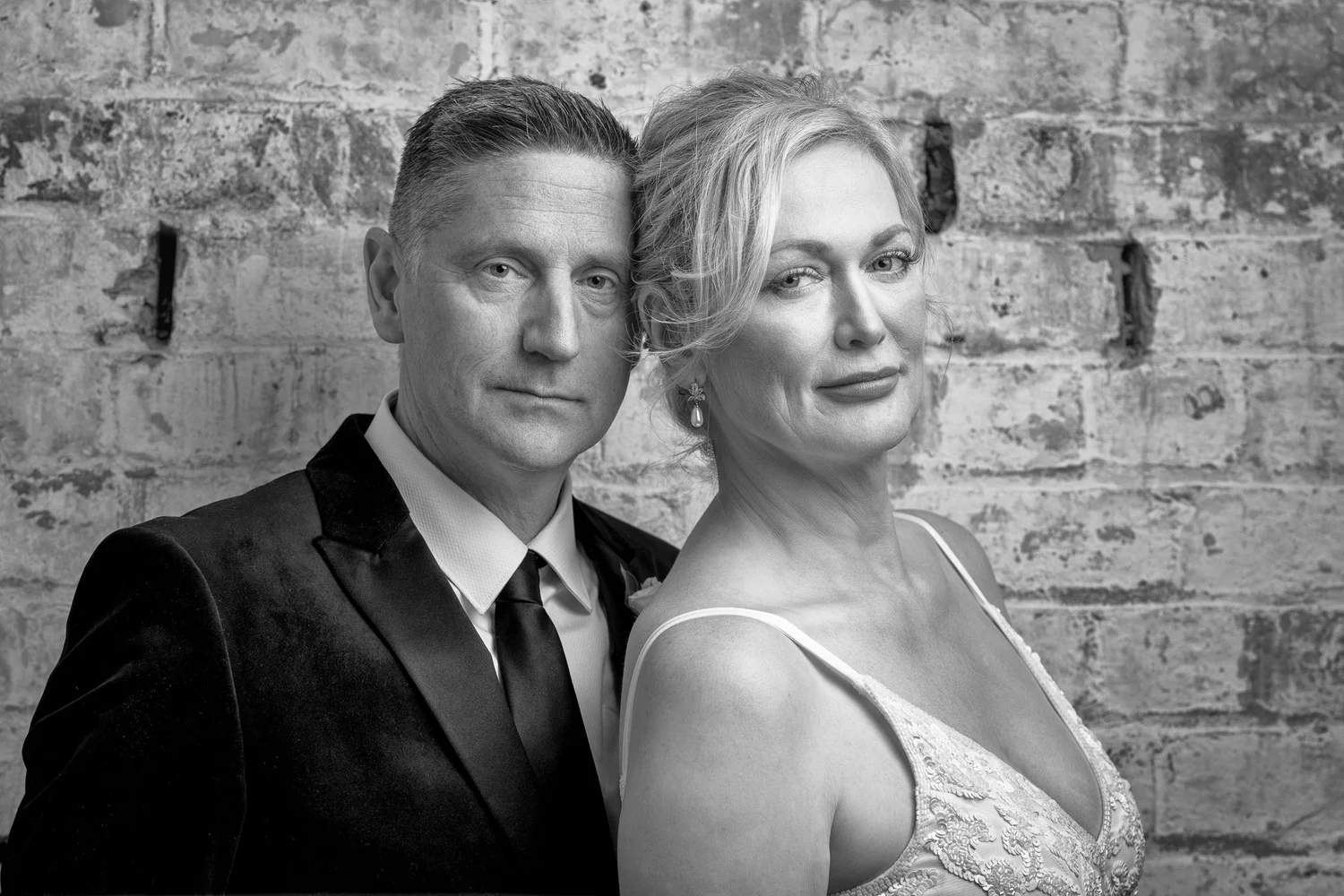 Black and white photo of the couple against a brick wall