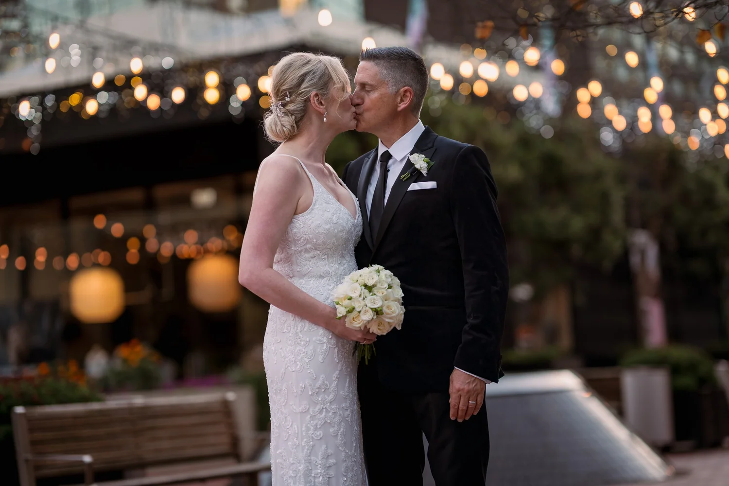 Darren kisses Shannon's cheek under festoon lights