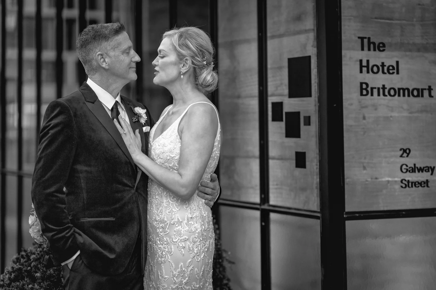 Black and white photo of the couple beside the hotel sign