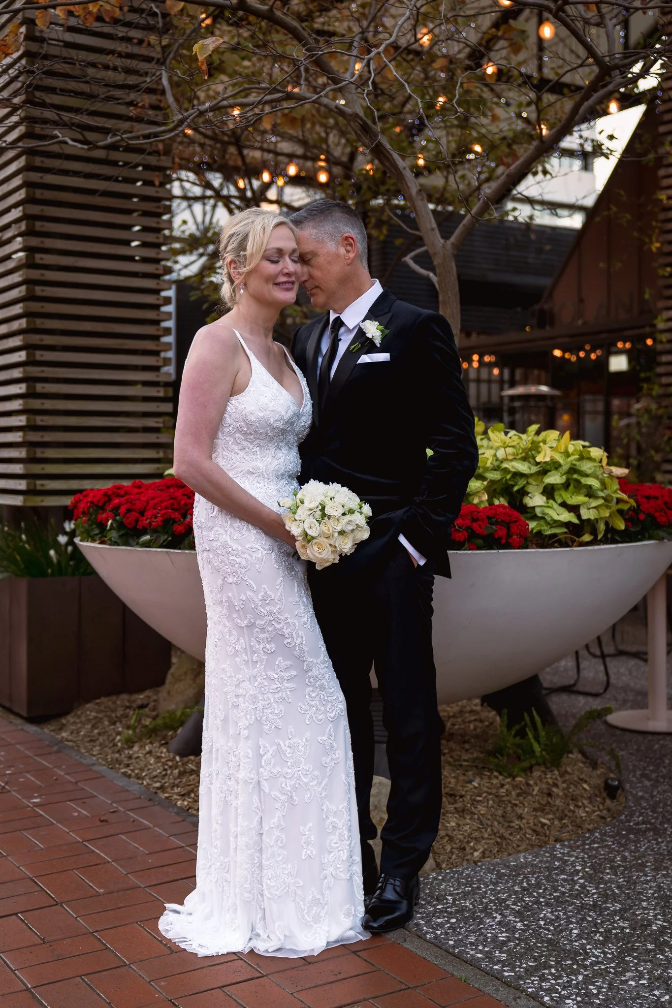 Shannon and Darren beside a planter of red flowers