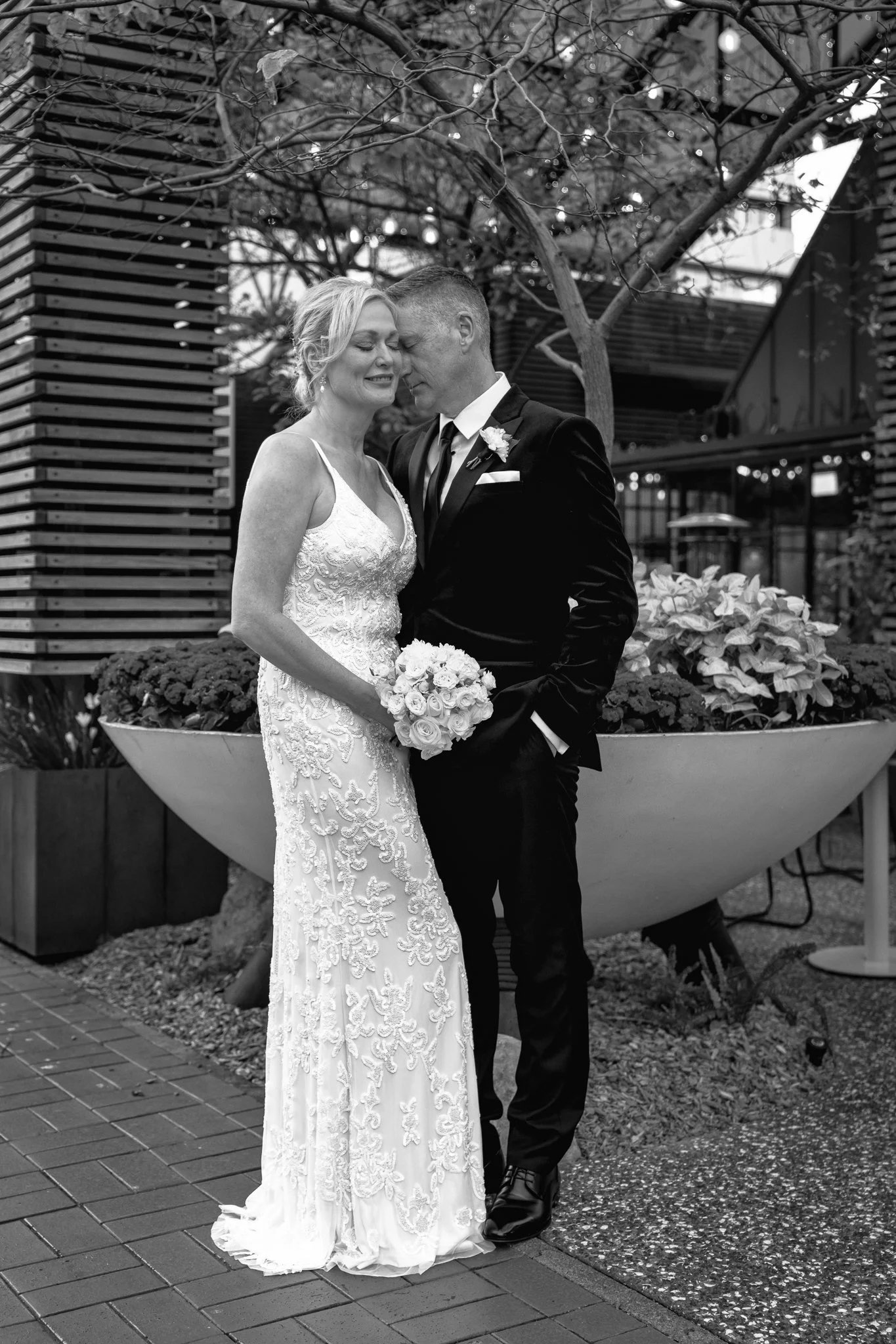 Black and white photo of the couple beside a planter