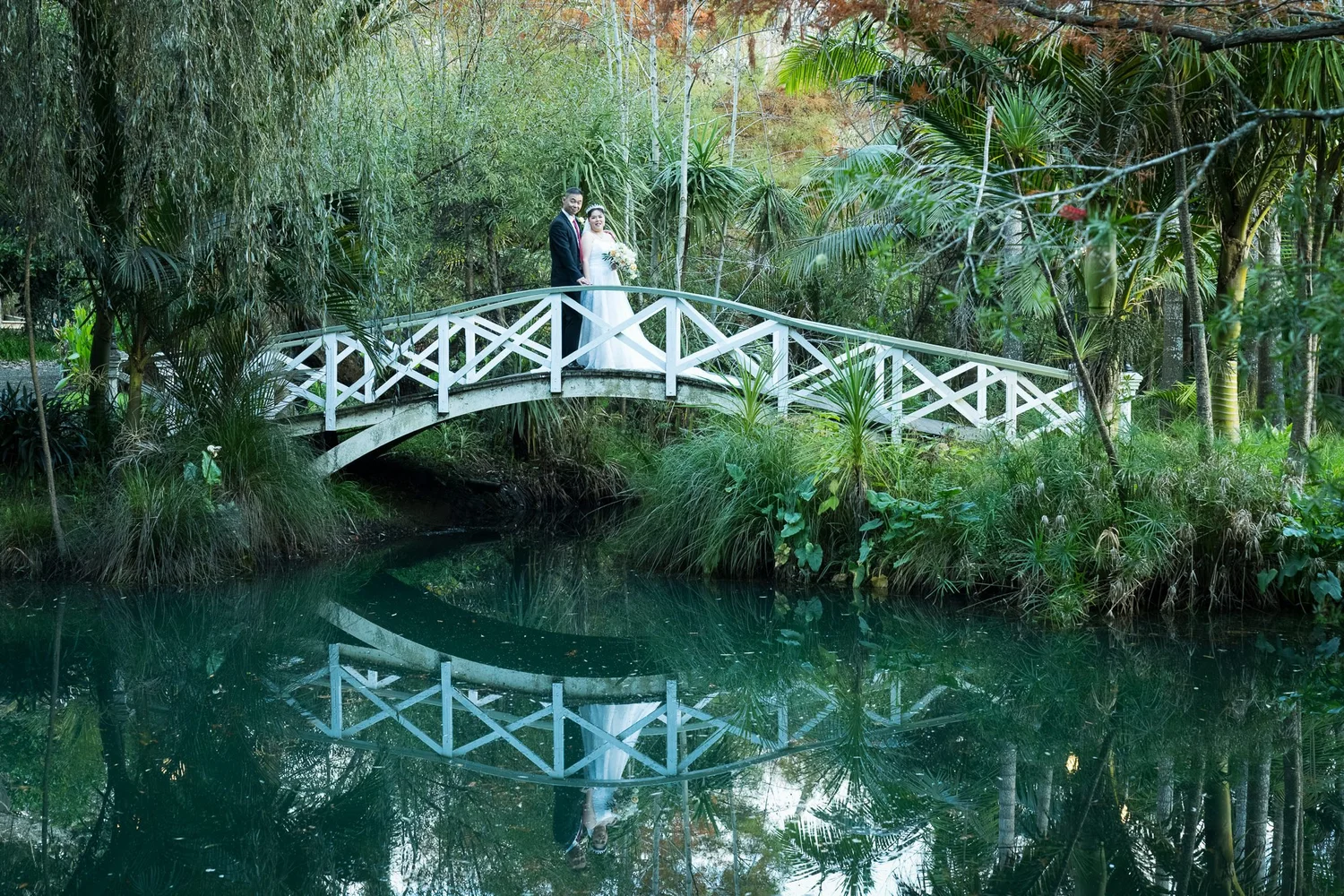 Stephanie and Jankai on the white bridge over the still pond
