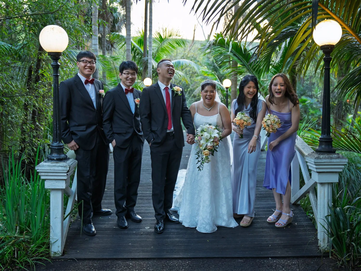 The bridal party on a garden bridge between lamp posts