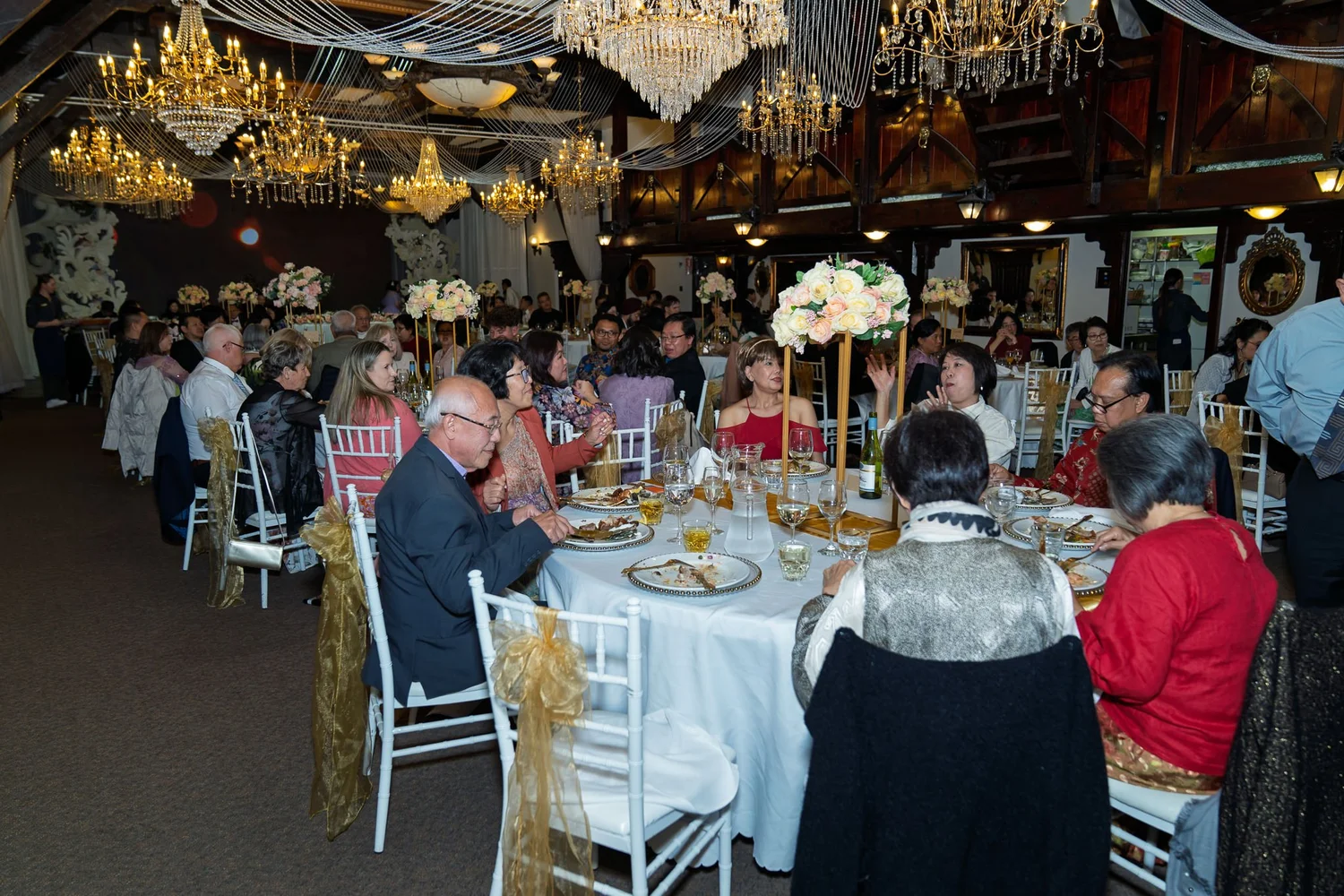 Guests at round tables under chandeliers