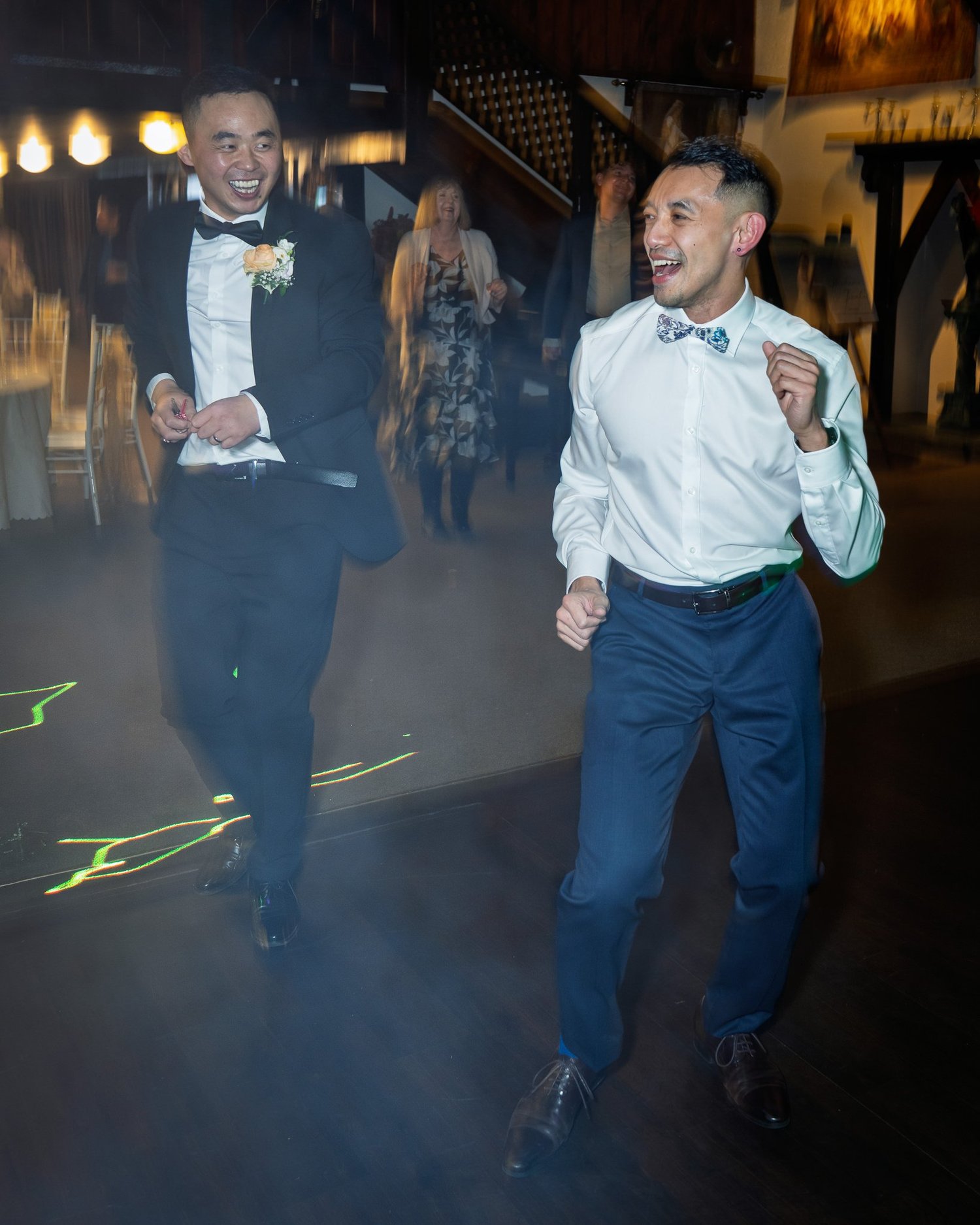 Two groomsmen dance across the floor