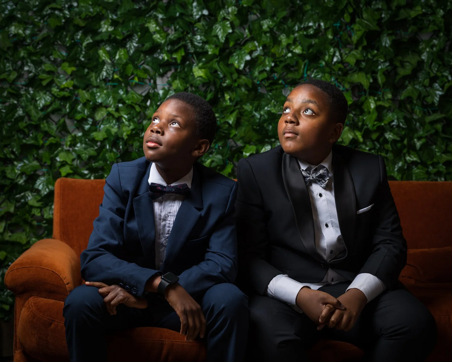 Two young guests in suits sit on a velvet sofa