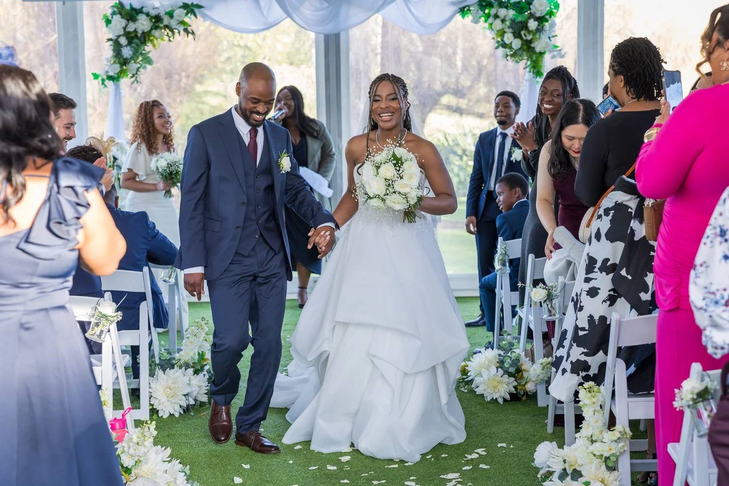 Chiedza and Foster walk back up the aisle past their guests
