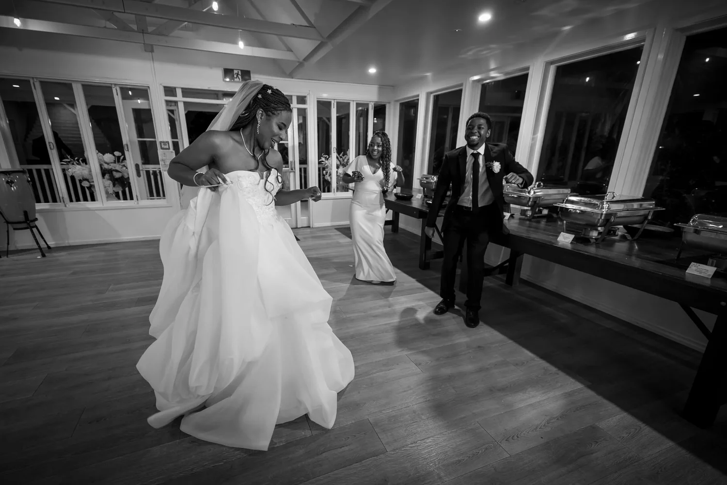 Black and white photo of Chiedza and Foster dancing into the reception