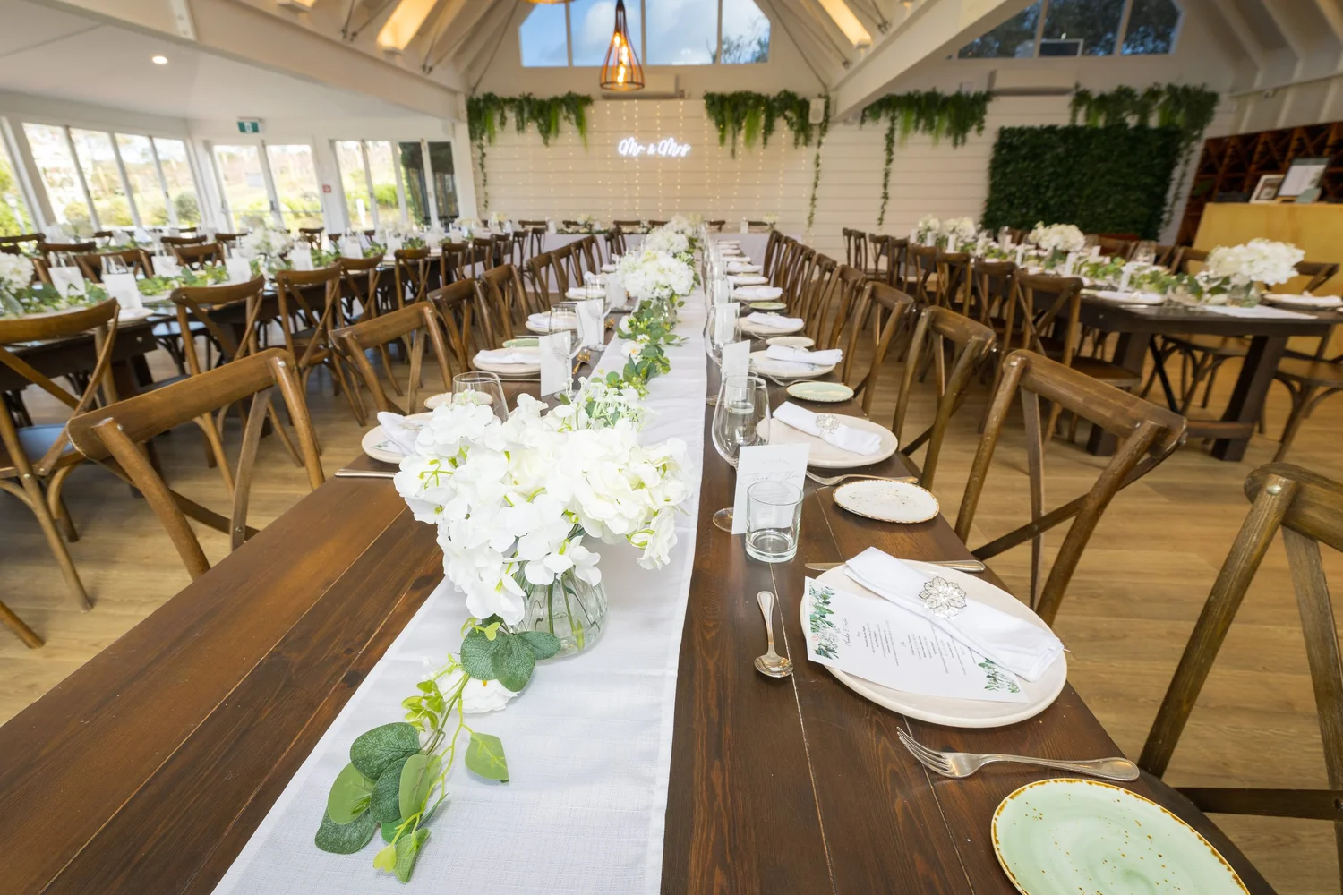 Long reception tables set with white flowers and greenery
