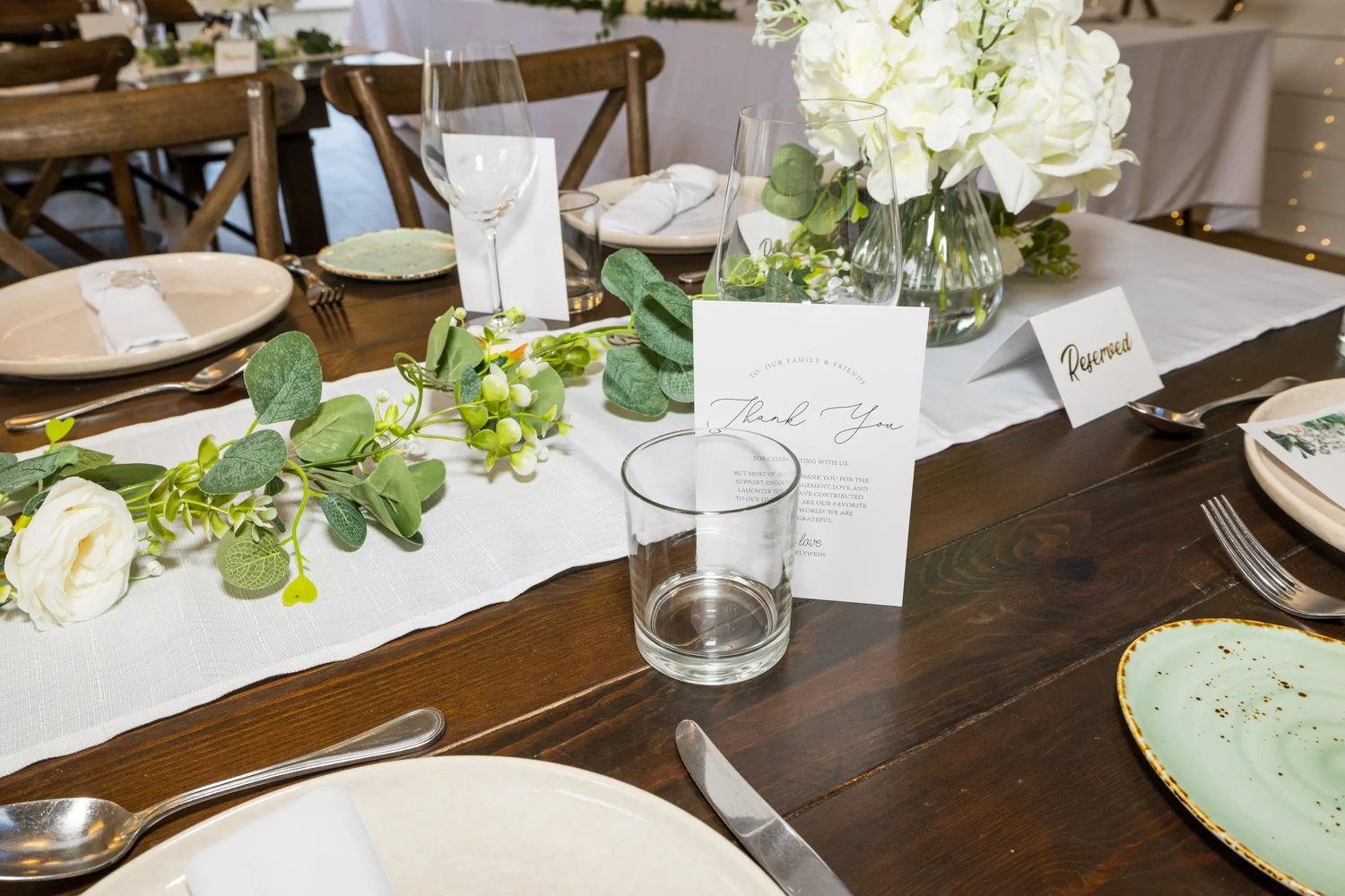 A reception table decorated with eucalyptus and white flowers