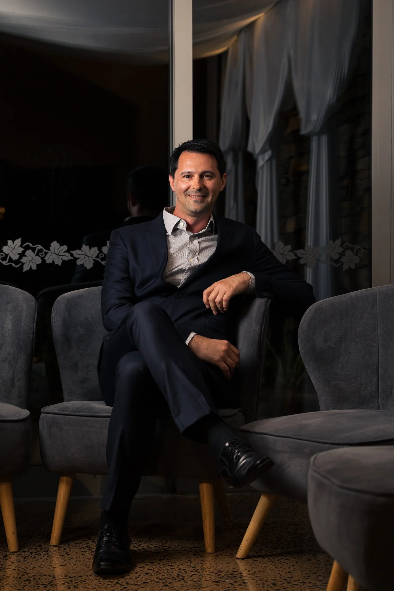 A guest seated on a grey armchair for an evening portrait