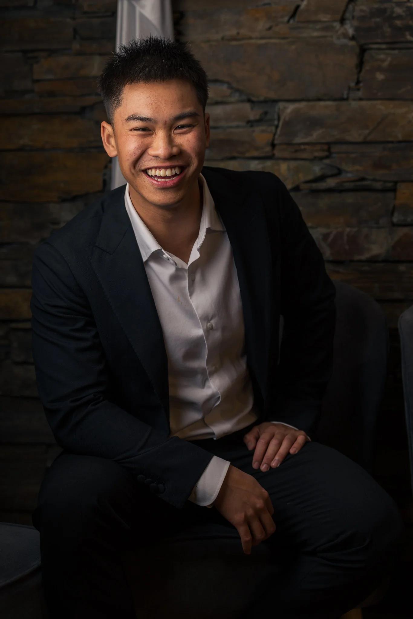 A smiling guest seated against a stone wall