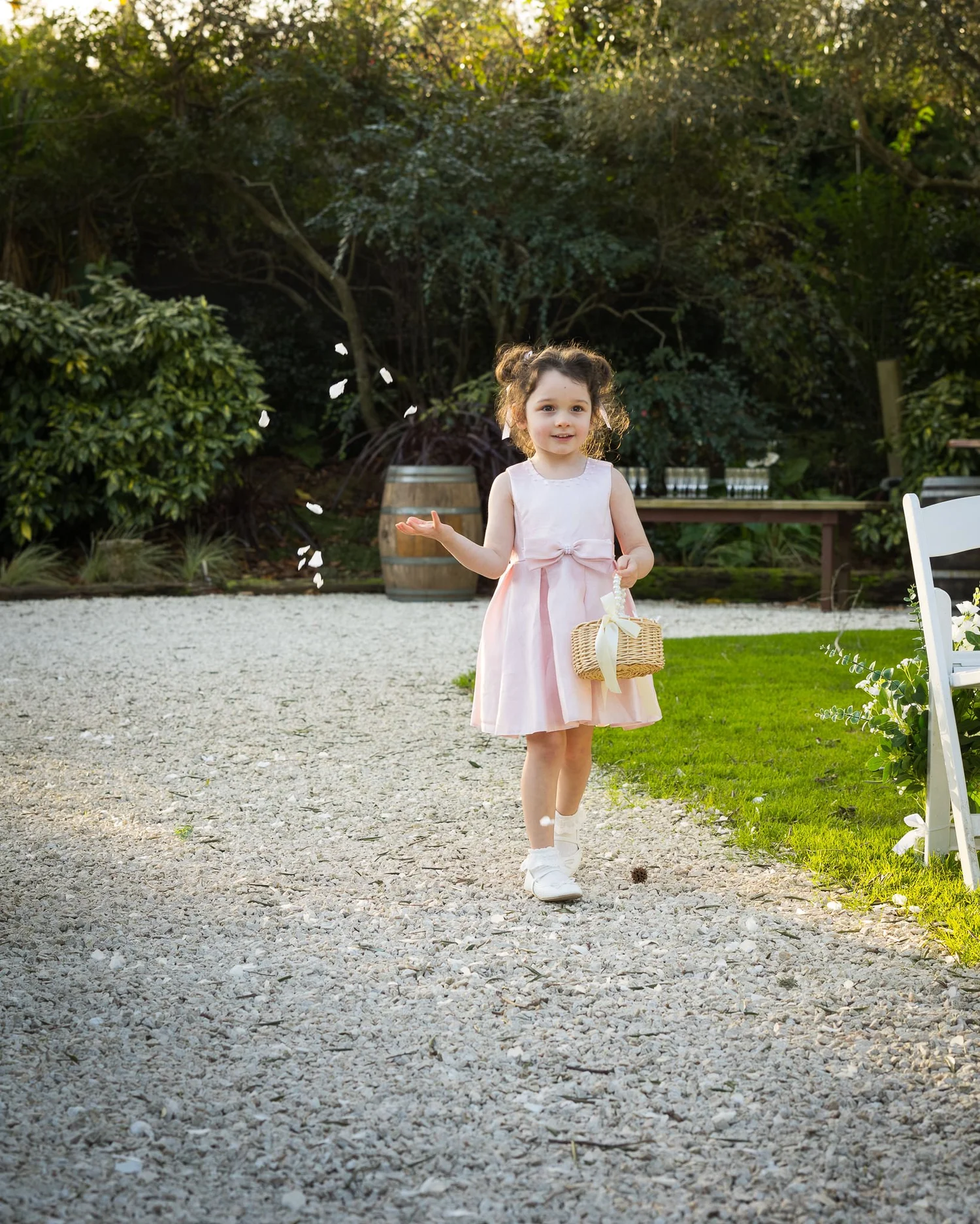 A flower girl walks down the gravel aisle at Markovina Vineyard Estate