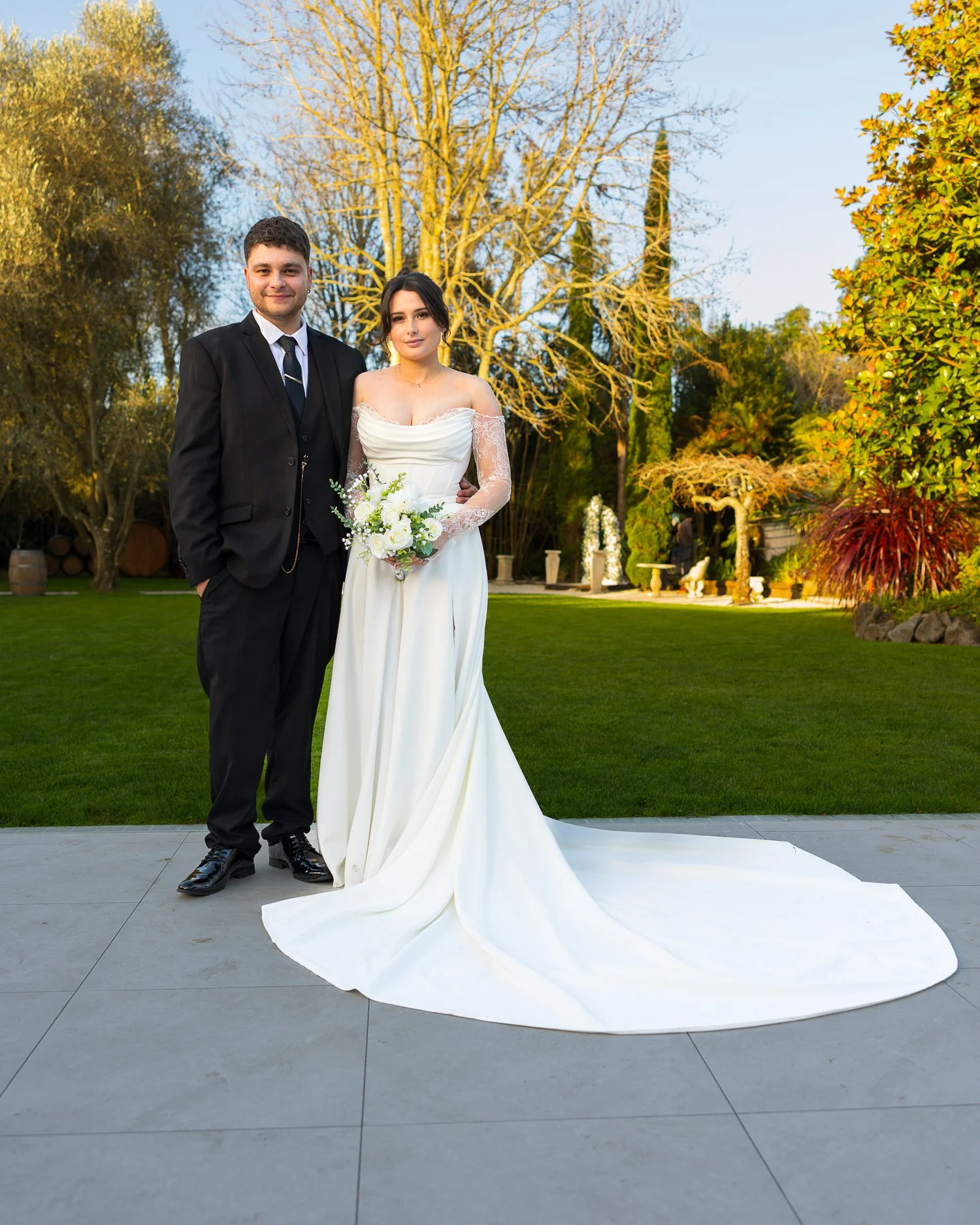 Paige and Connor stand together on the lawn in the late-afternoon sun