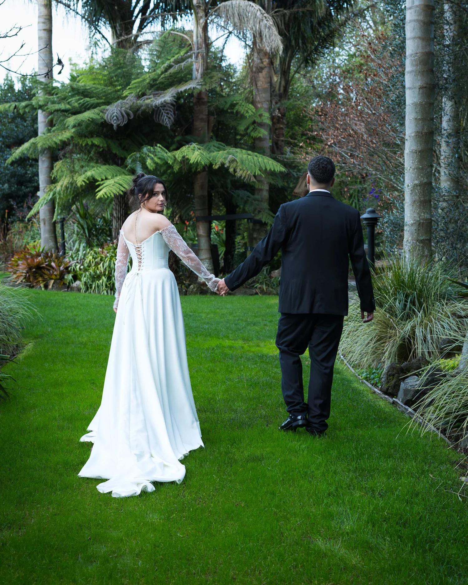 Paige and Connor walk hand in hand across the lawn