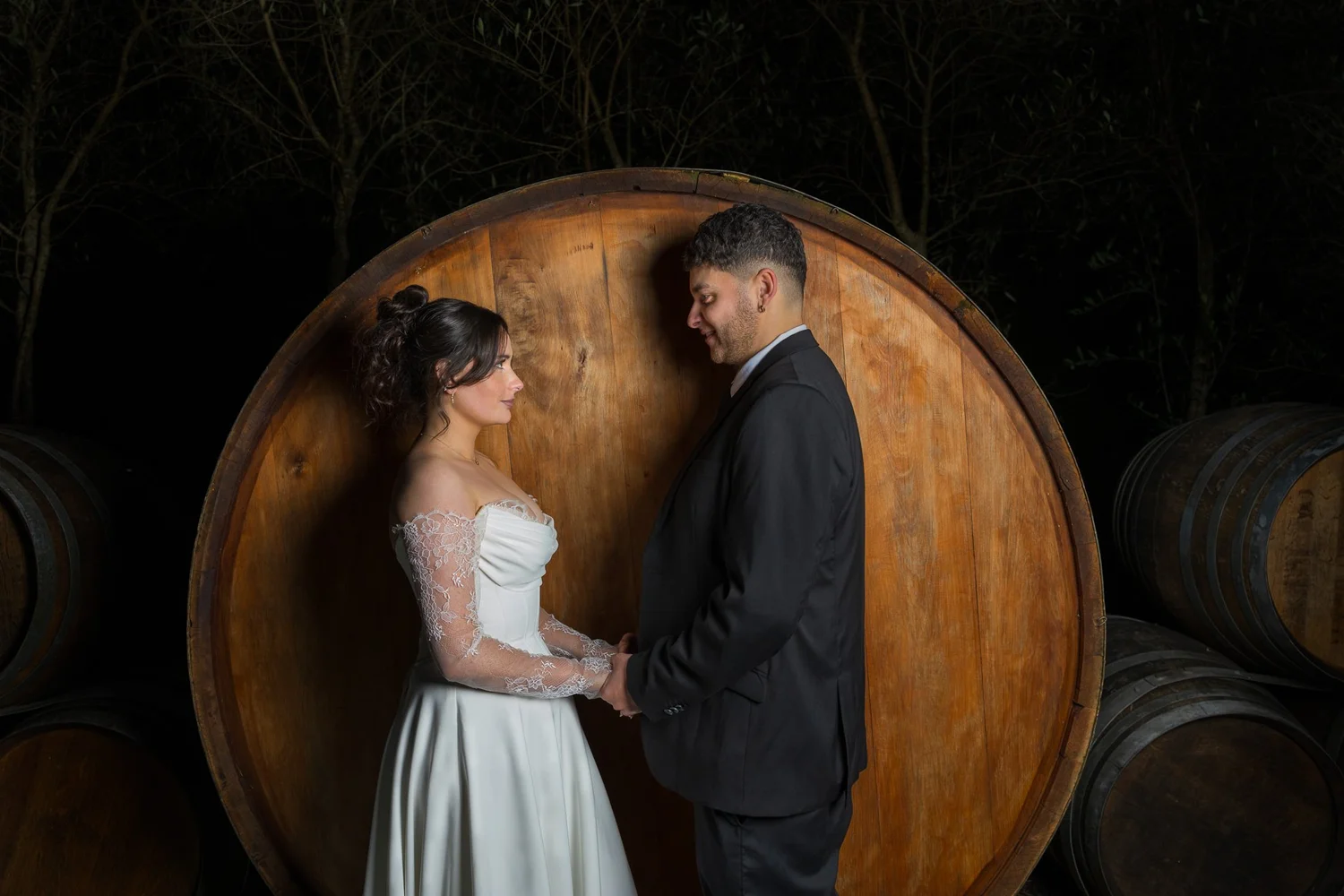 Paige and Connor hold hands in front of a giant wine barrel