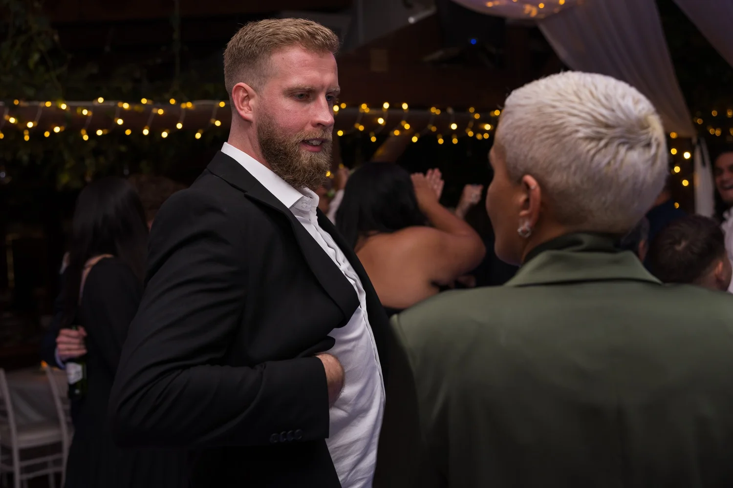 Guests chat on the dance floor under fairy lights